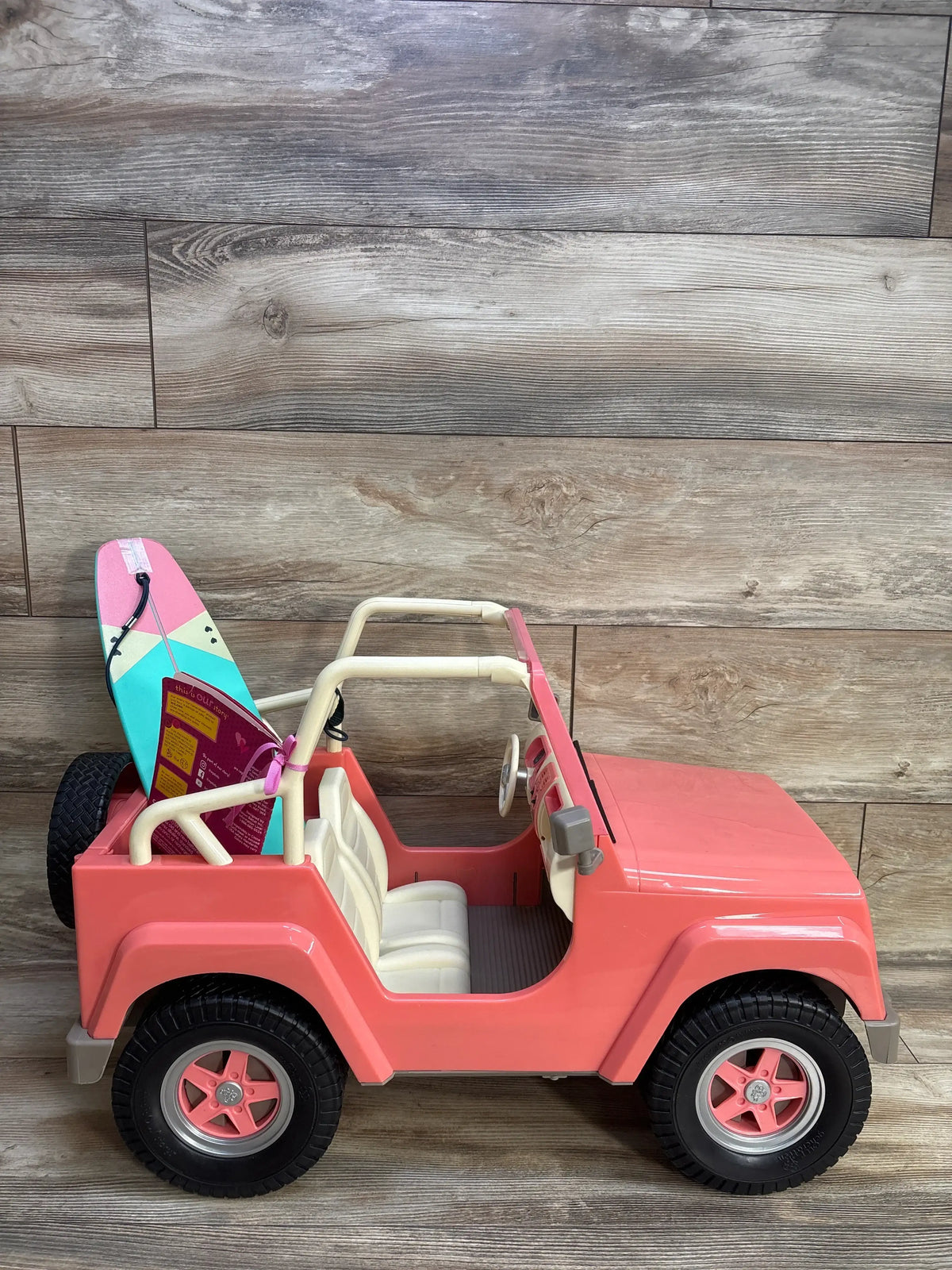 Side view of Our Generation Off-Roader 4x4 Doll Vehicle in pink showcasing cream seats, roll bars, and rear surfboard