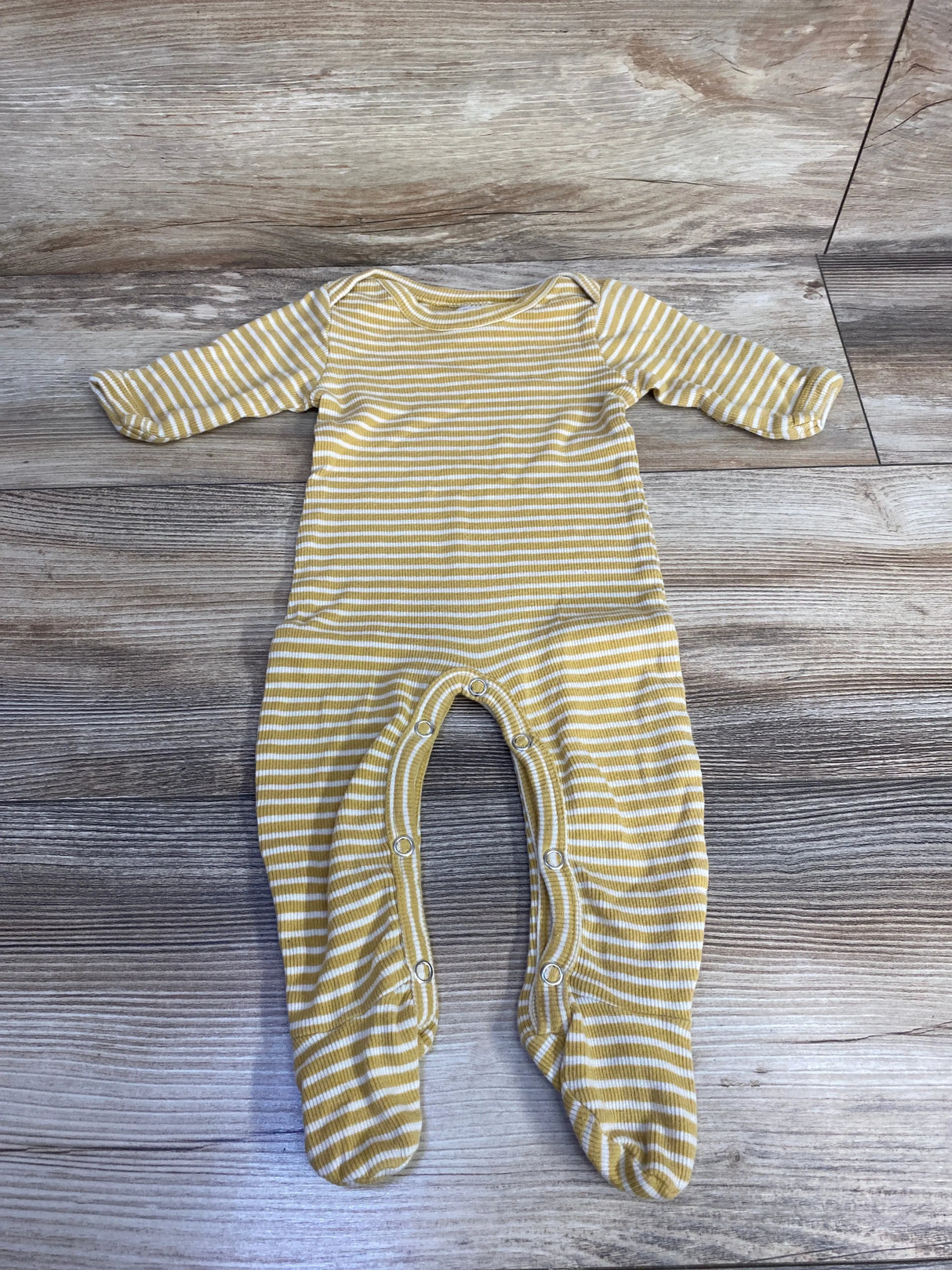 Yellow and white striped long-sleeve baby onesie with footies on wooden floor