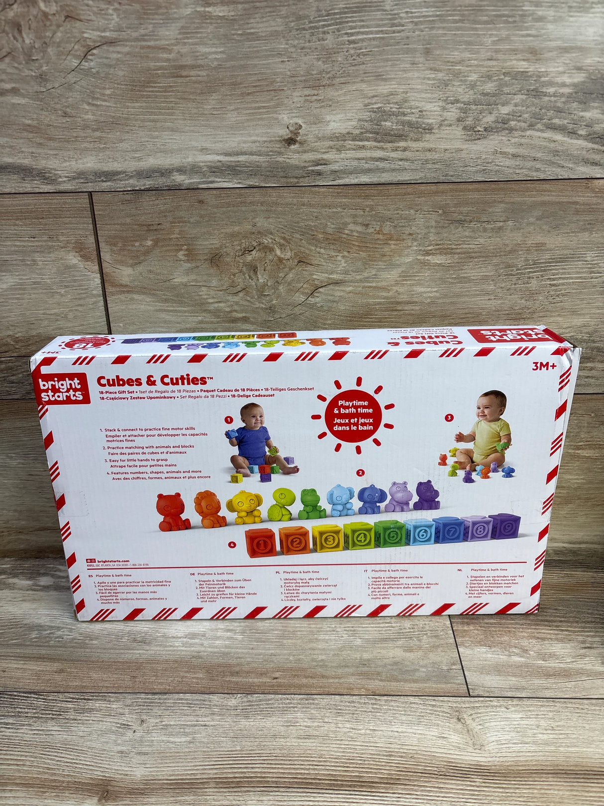 Front view of Bright Starts Cubes & Cuties 18-piece gift set showcasing colorful numbered stacking cubes and animal figures on a wood floor background