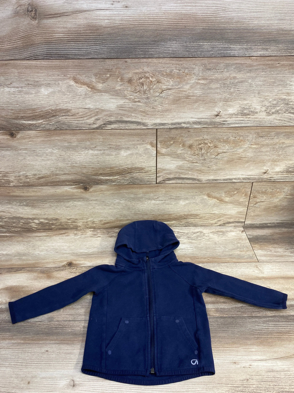 Navy blue zip-up hoodie with front pockets on wooden floor background