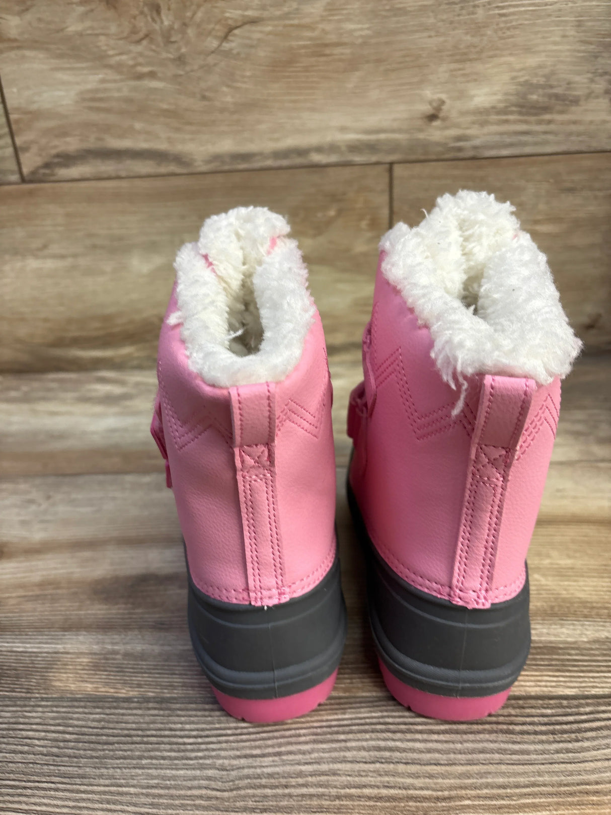 Rear view of Cat & Jack Denver winter boots showcasing white faux-fur lining, gray rubber soles, and pink upper on wood plank background