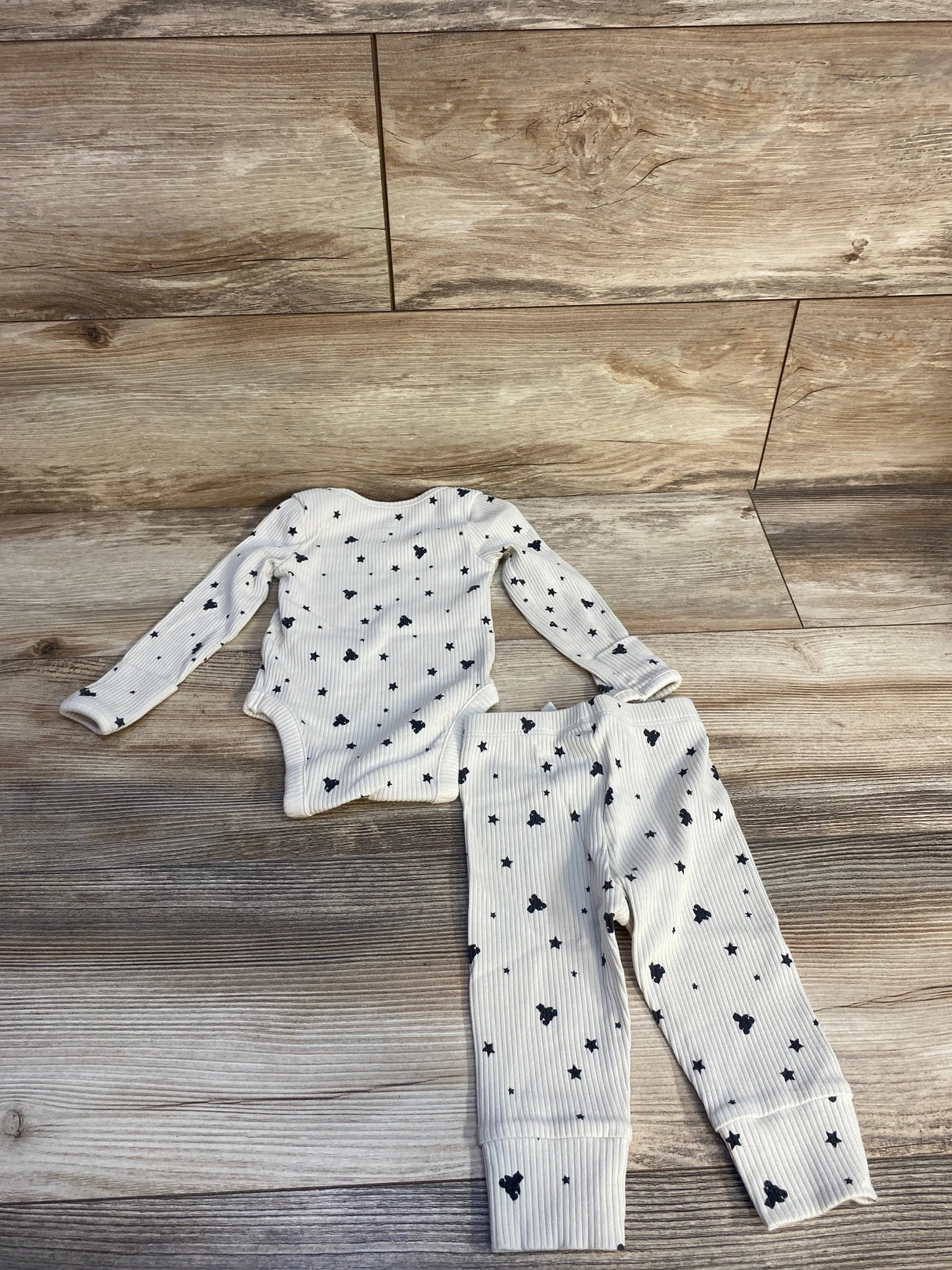 Top-down view of Baby Gap ribbed bodysuit and pants set in tan showcasing bear and star prints on a wooden floor