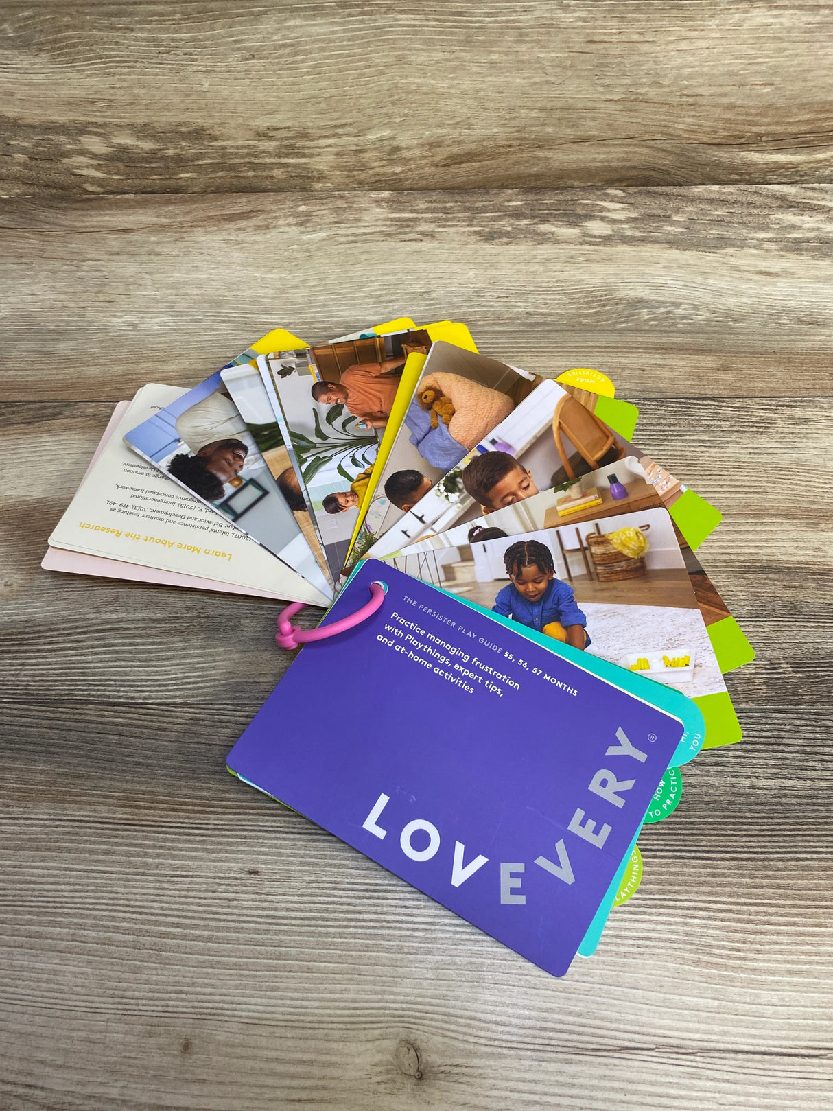 Lovevery play guide cards for 55-57 months, with parenting and play activity tips on wooden surface