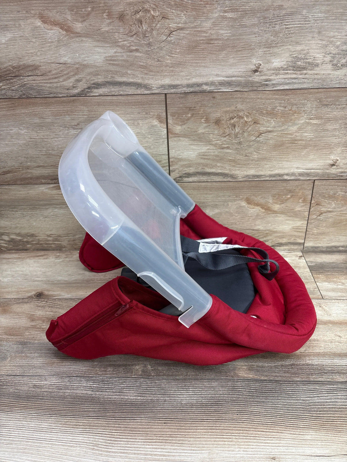 Angled view of red Inglesina Fast Table Hook-On High Chair with clear tray and safety harness on a wood-look floor