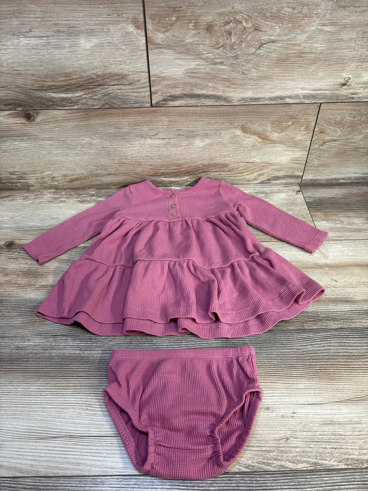 Mauve ribbed long sleeve baby dress with matching diaper cover on wood background
