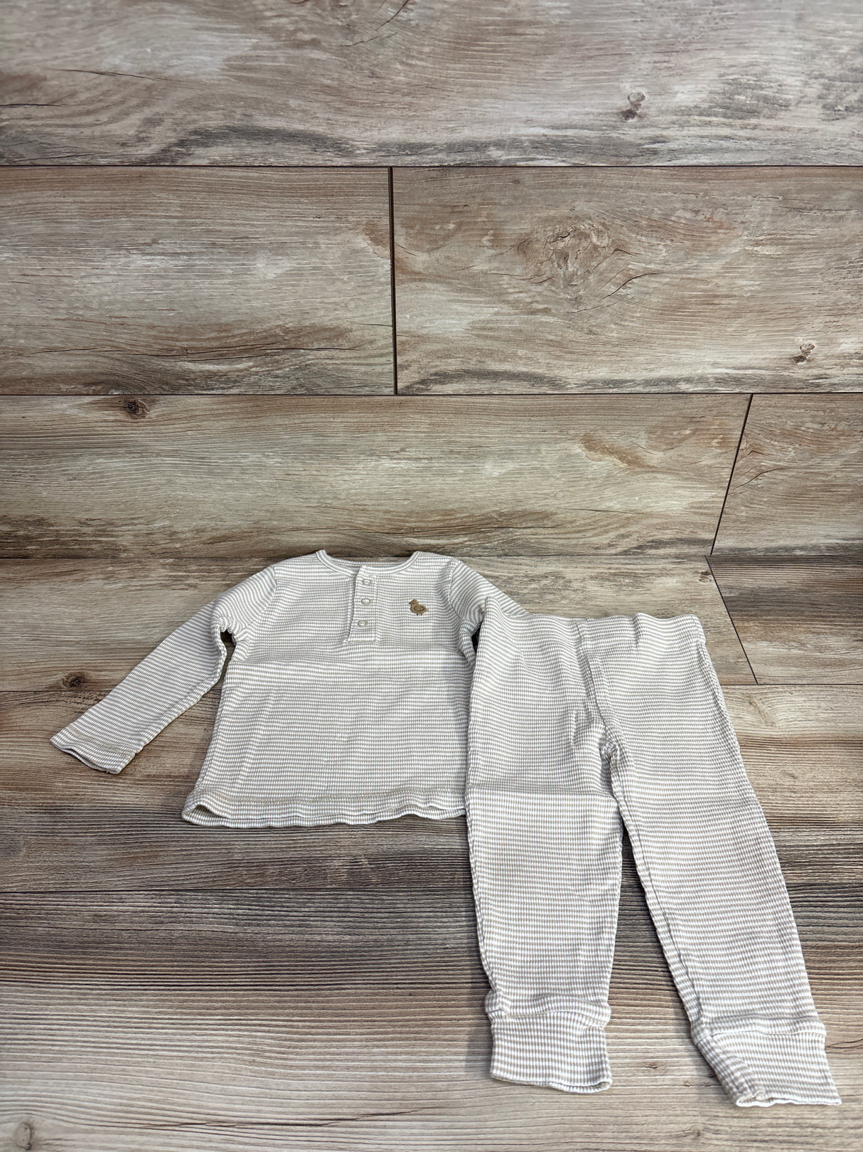 Children's light beige and white striped long sleeve top with buttons and pants set on wood background