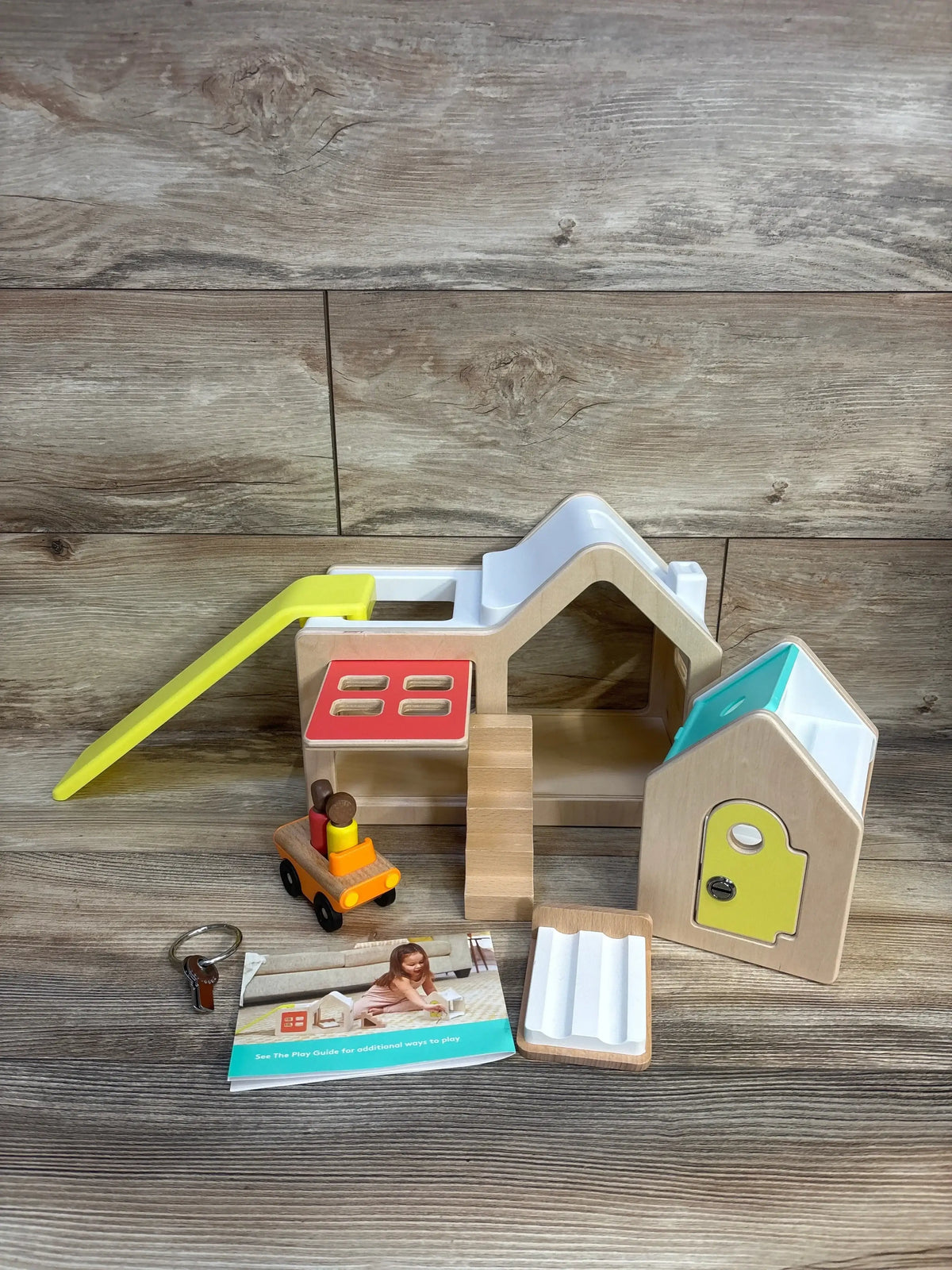 Wooden playhouse toy with colorful parts, slide, car, and play guide for kids' imaginative play