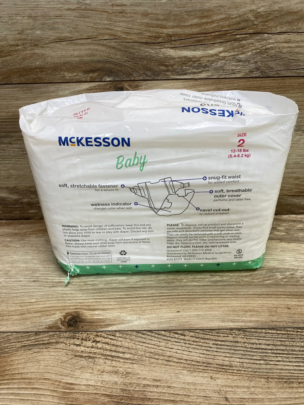 Front view of McKesson Baby Diapers size 2 sealed pack showcasing snug-fit waist and wetness indicator features with wood plank background