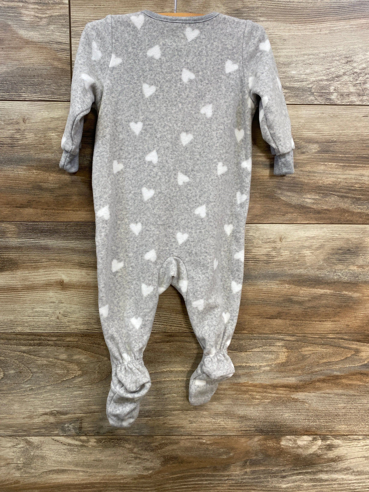 Gray fleece baby sleeper with white heart pattern on wood background