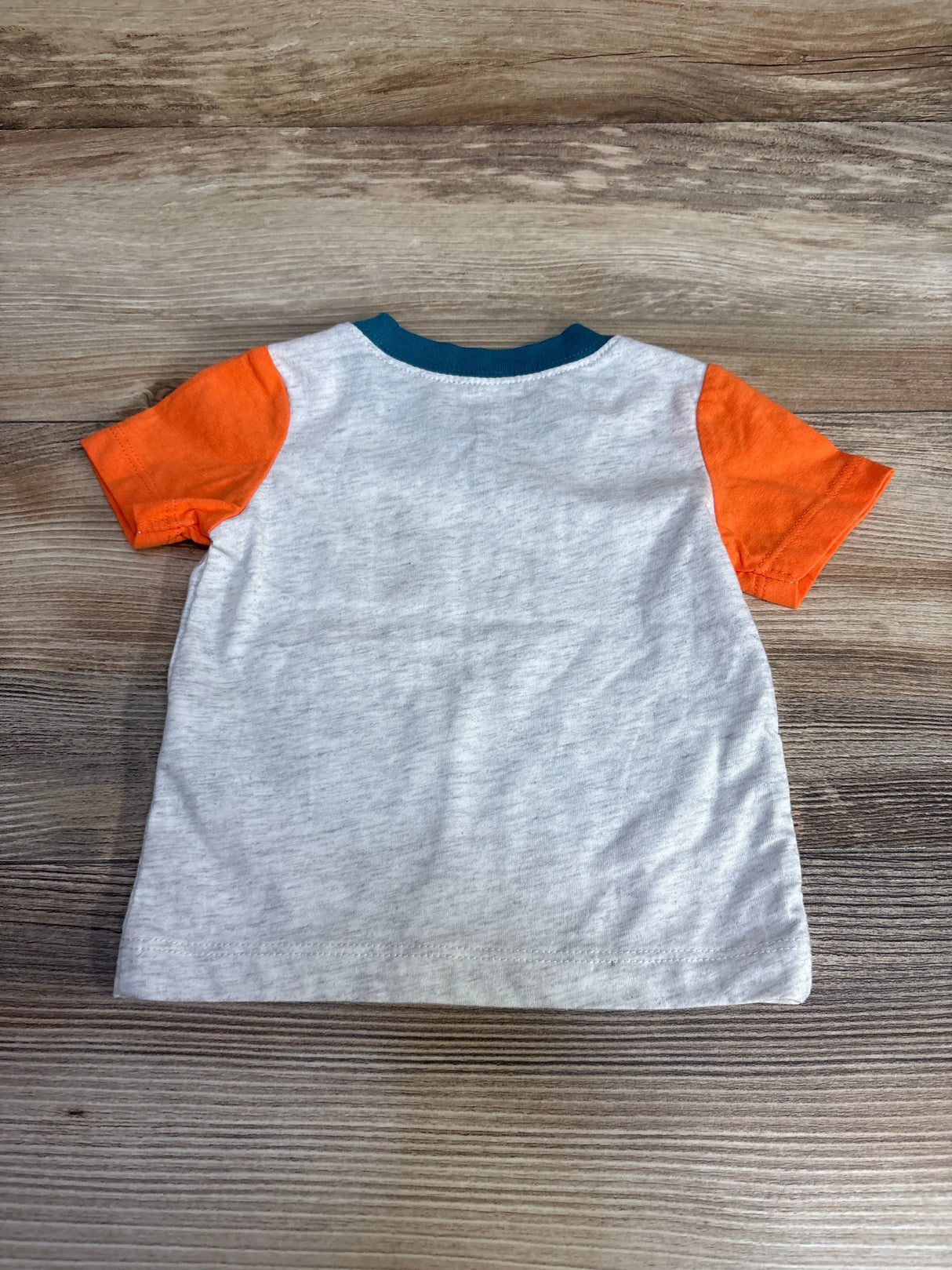 Back view of Carter’s short sleeve baby shirt size 3M showcasing heather grey body, orange sleeves and teal neckline on wood background
