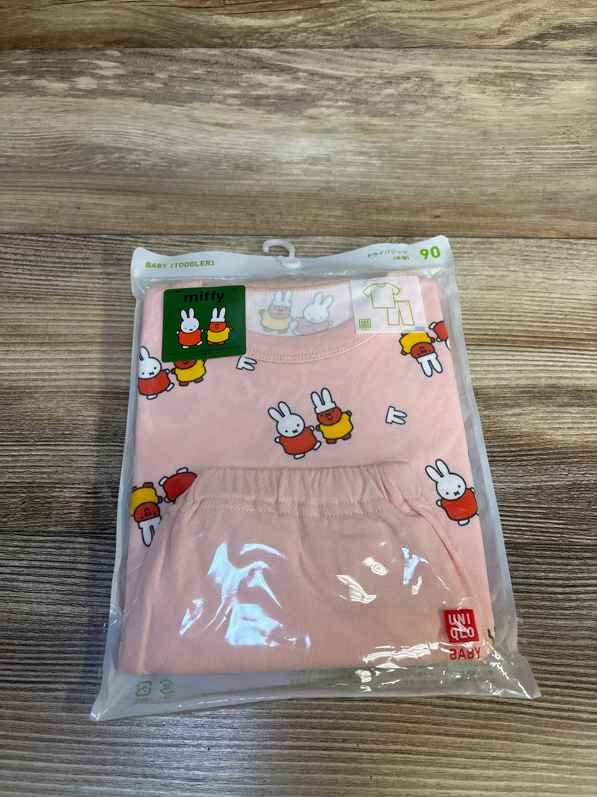 Front view of Uniqlo Miffy 2-piece toddler pajama set size 90 with pink bunny print and elastic-waist pants in clear packaging