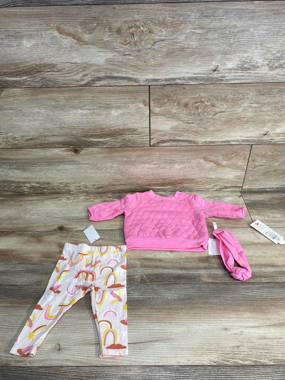 Baby girl outfit set with pink quilted long-sleeve top, rainbow leggings, and matching headband