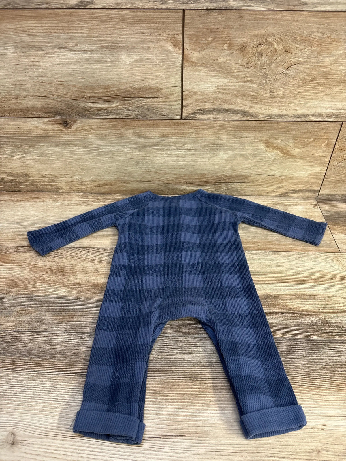 Flat lay of Mud Pie blue waffle-knit checkered coverall, 6-9m, with long sleeves and rolled cuffs on wood background