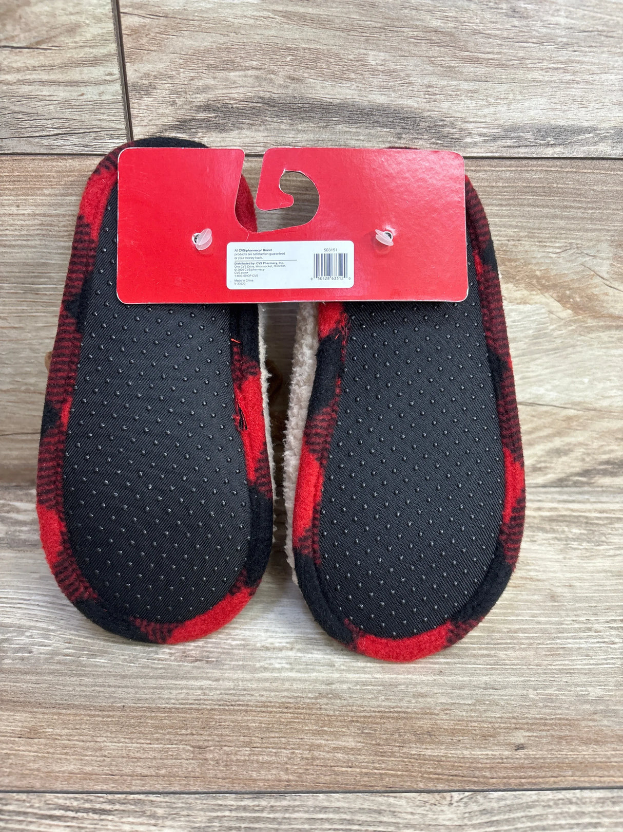 Kids red and black plaid slippers with non-slip soles on wood floor