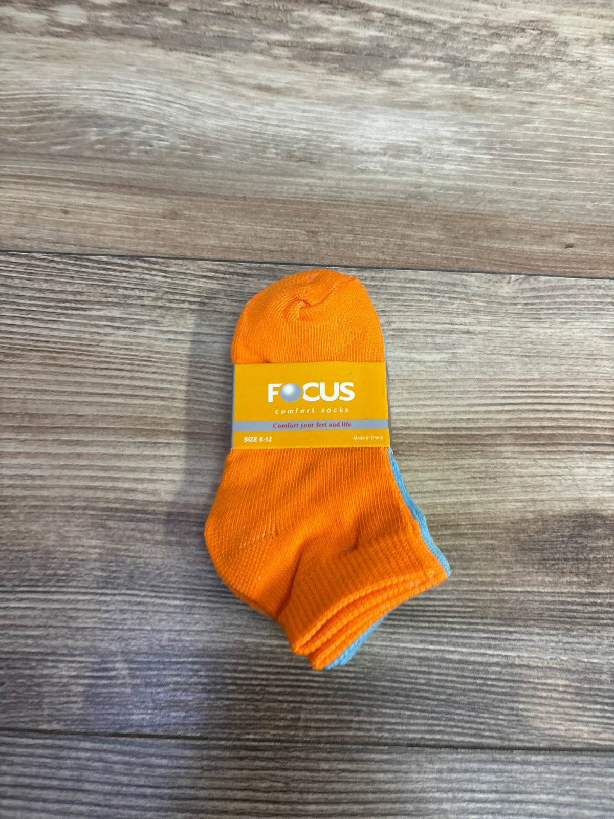 Pair of orange and blue Focus comfort socks for kids size 0-12 on wooden surface