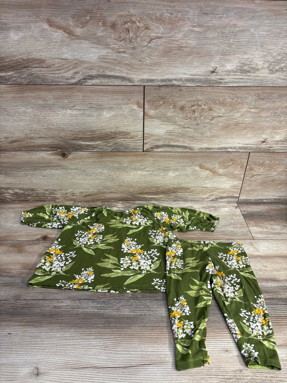 Green floral baby outfit set with long sleeve top and pants on wood background