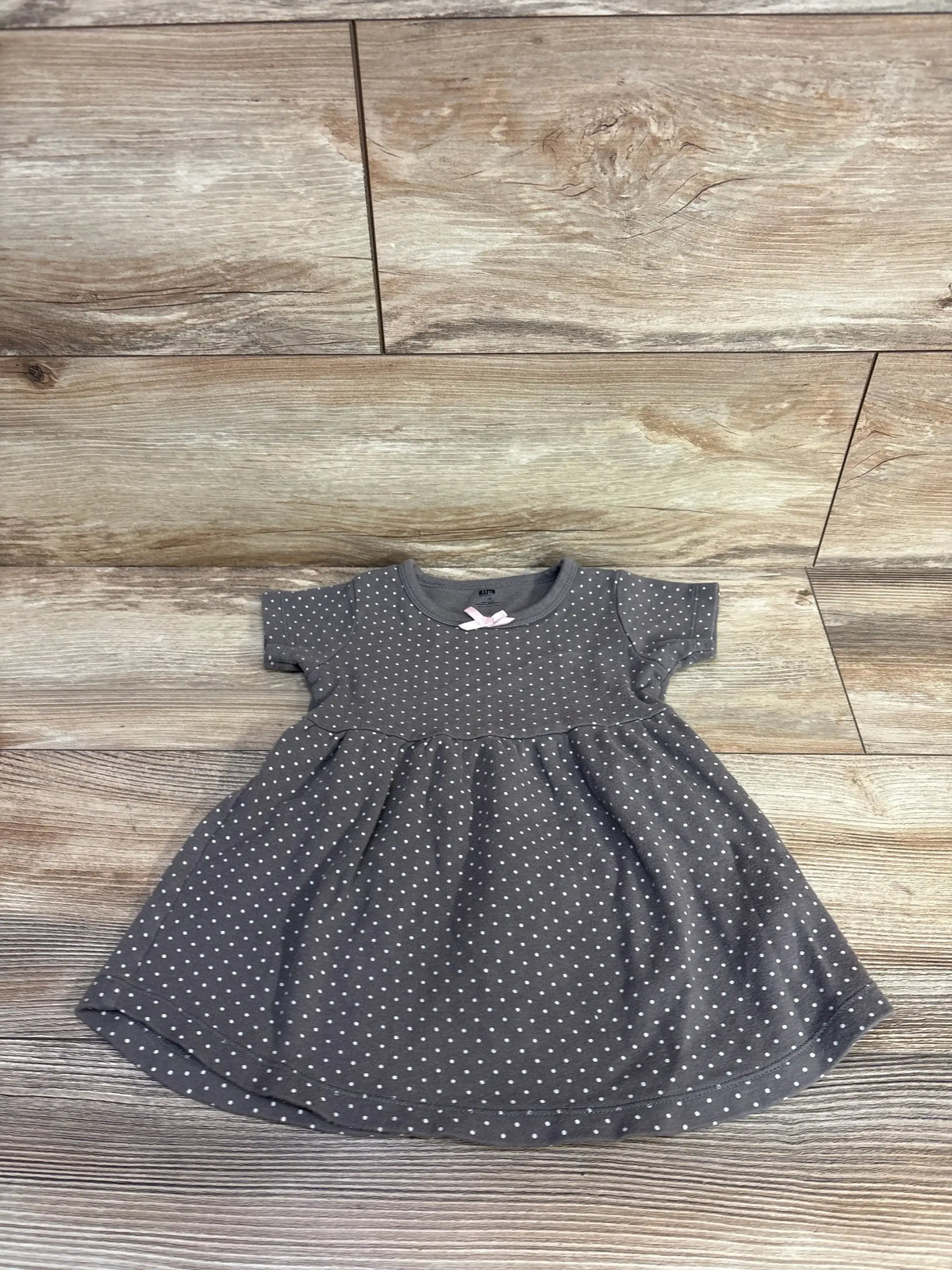 Flat lay of Hudson Baby brown polka dot 18-month dress showcasing short sleeves and gathered skirt on wood plank background