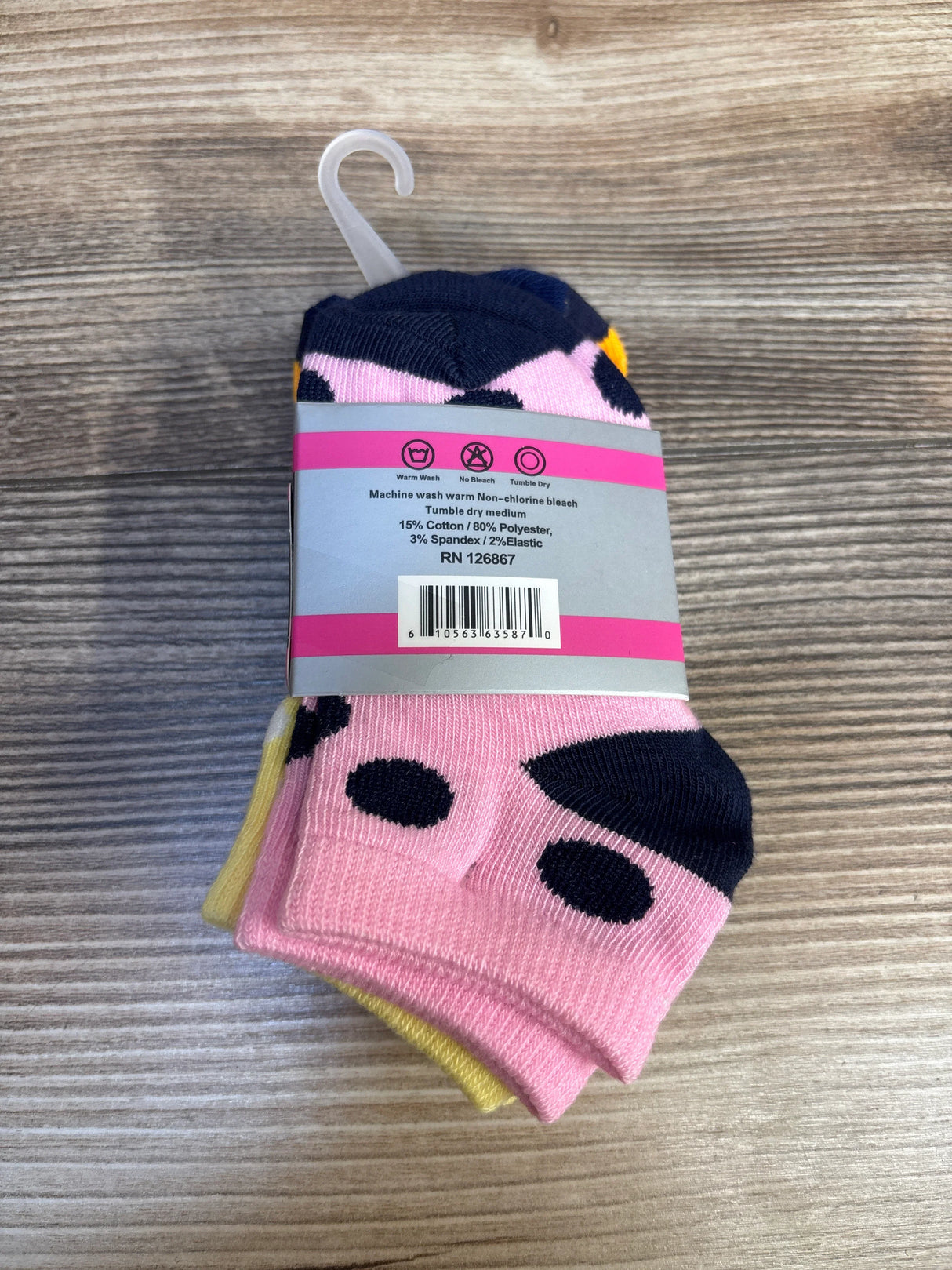 Pack of colorful baby socks with polka dot pattern on wood background