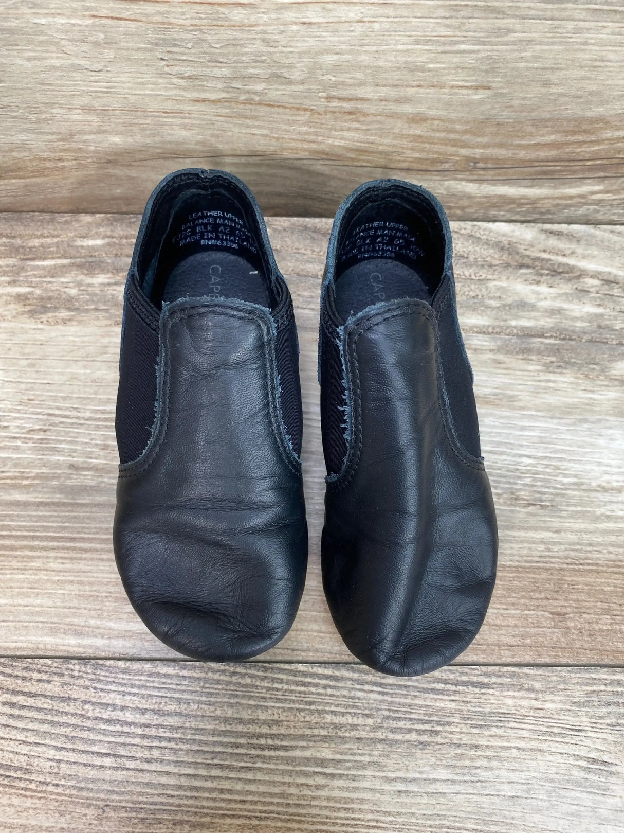Top view of Capezio jazz slip-on shoes size 10C showing leather toes and elastic side panels on wood floor
