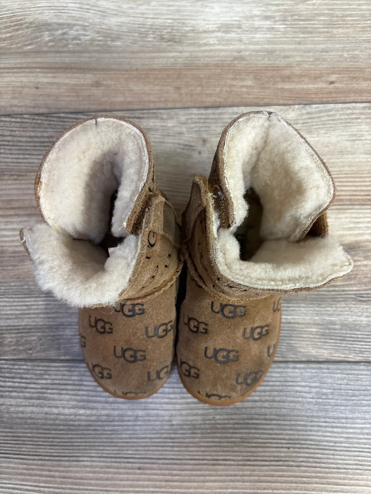 Top view of cozy brown UGG baby boots with plush lining on wooden floor