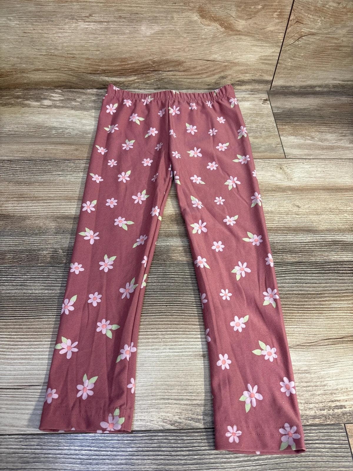 Front view of Derek Heart floral leggings showcasing the pink floral pattern and elastic waistband with a wood look floor background