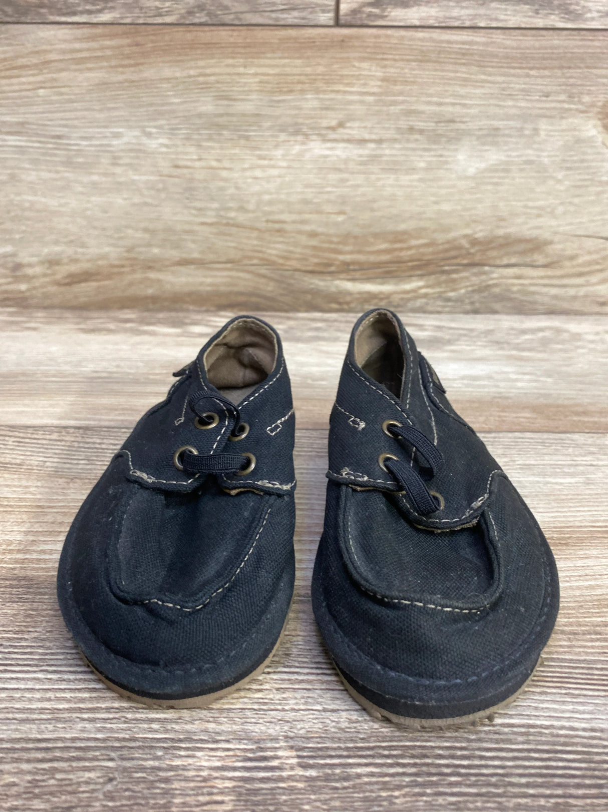 Pair of black toddler shoes with laces on a wooden surface, kids resale store item