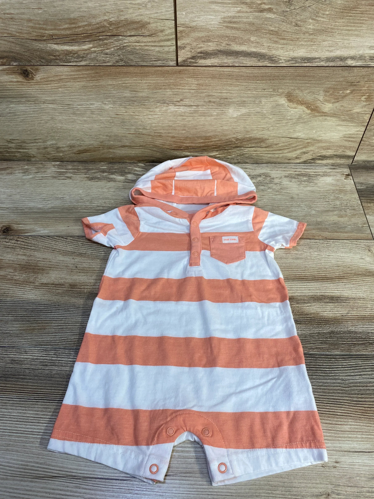 Flat lay of Carter's white and peach hooded romper (6-9 months) showing front and leg snaps and chest pocket on wood