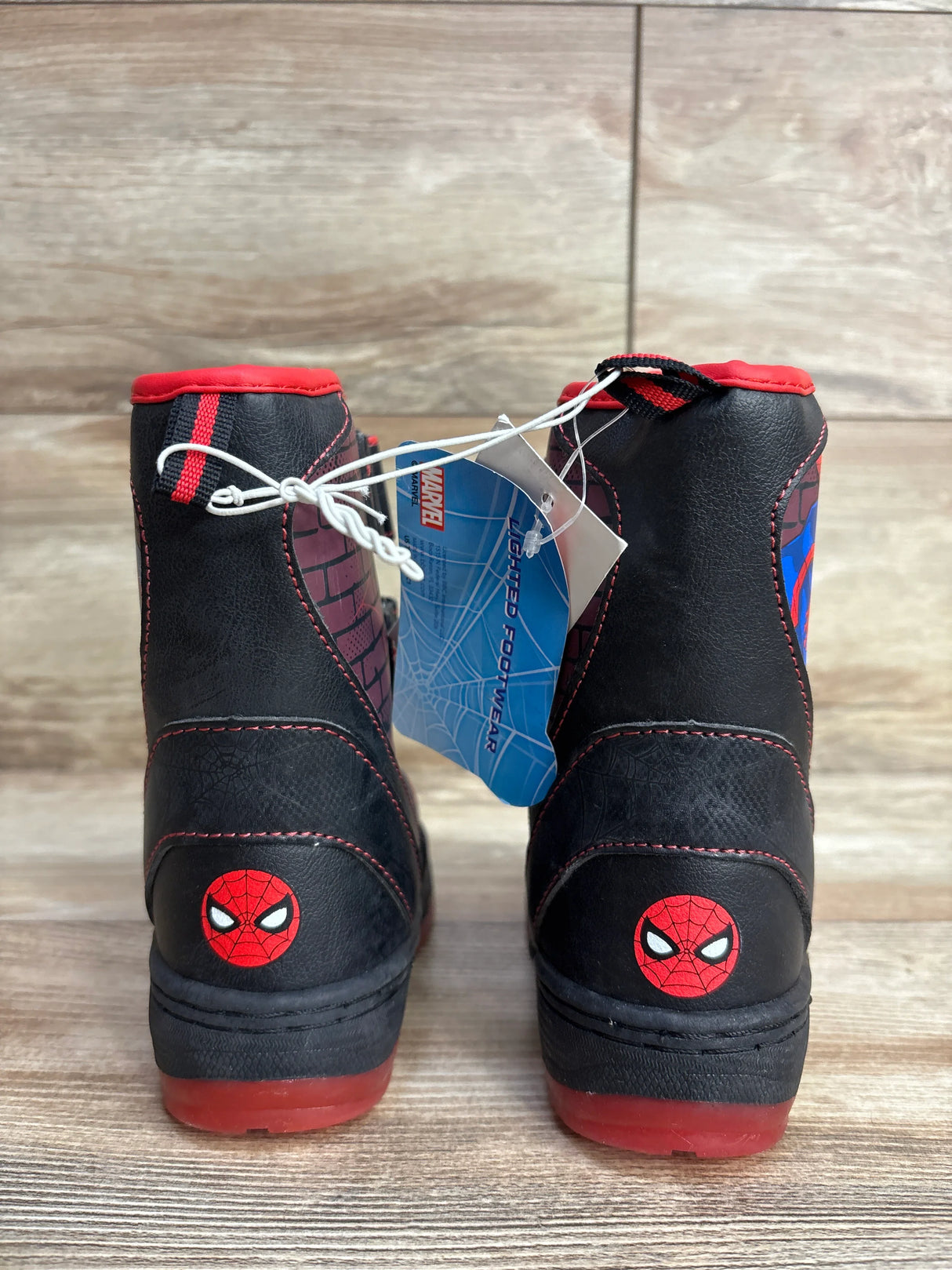 Back view of black and red Spider-Man lighted children’s boots with Marvel tag on wooden floor