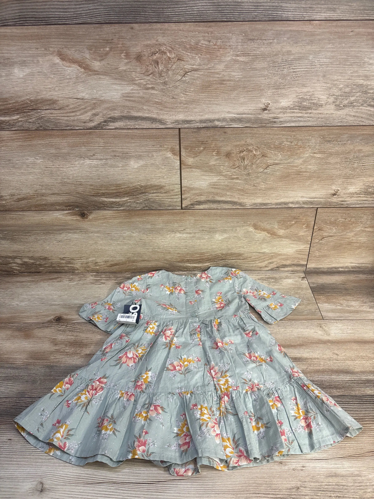 Front view of green Oshkosh floral dress size 2T showcasing short sleeves and tiered skirt on a wood floor