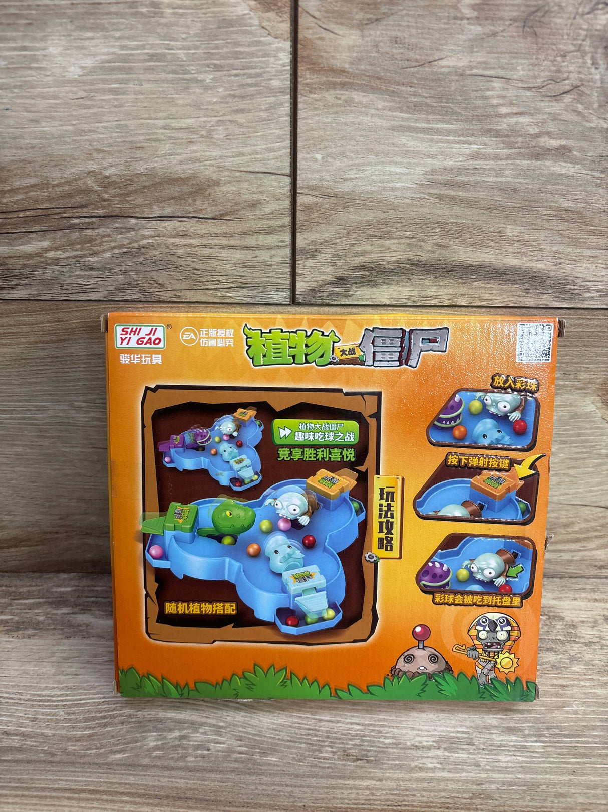 Plants vs Zombies themed children's tabletop game with colorful balls, blue play area, and character figures on wooden floor