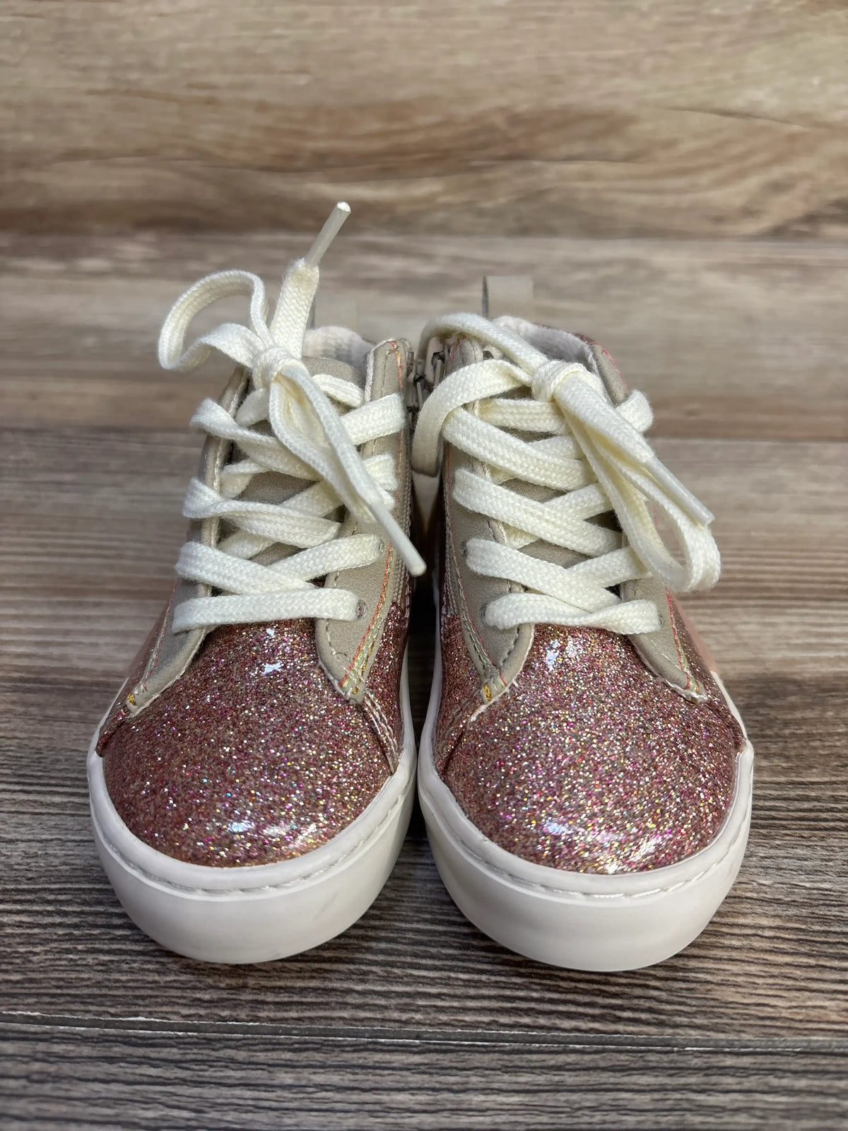 Front view of Zara glittery high top sneakers in pink showcasing white laces on a wood floor