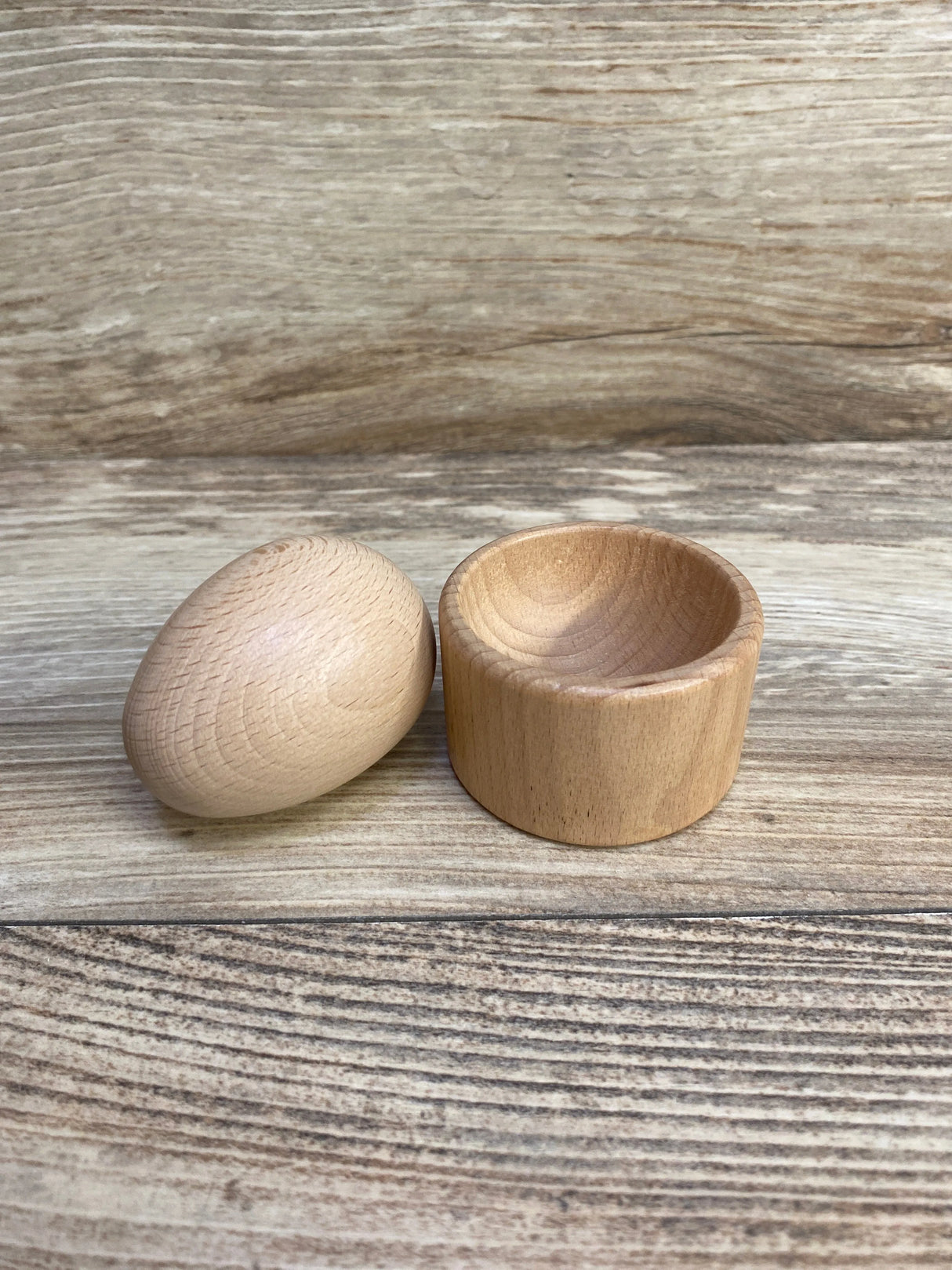 Natural wooden egg and cup set on rustic wooden surface, Montessori toy