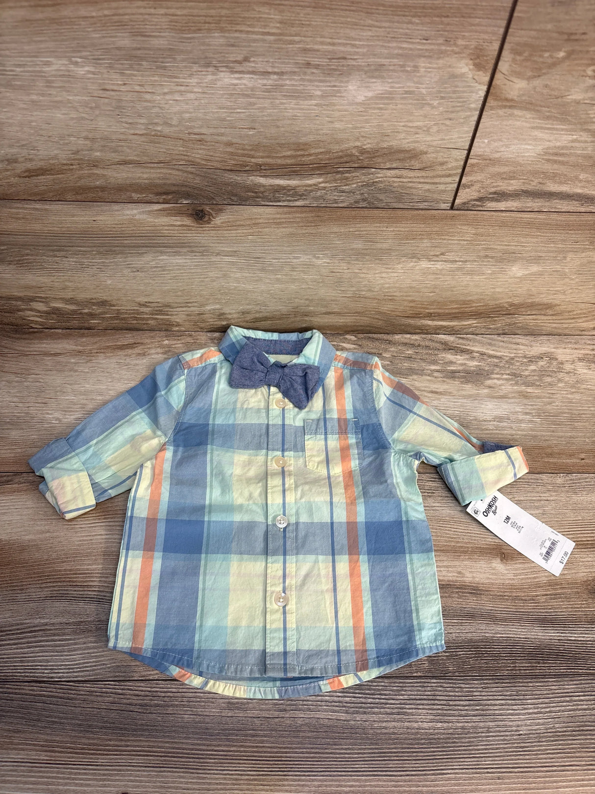 Top-down view of OshKosh 12M baby boys' long-sleeve plaid button-down shirt showcasing attached blue bow tie on wood floor