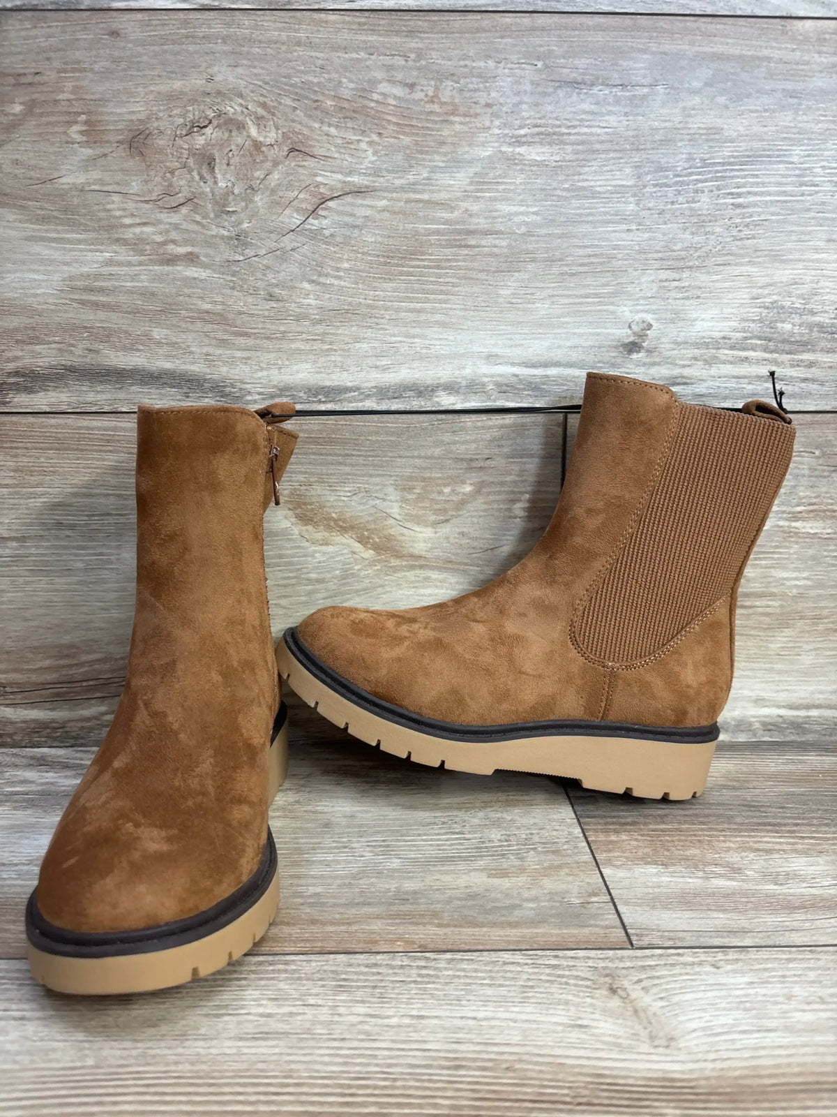 Brown suede children's ankle boots with side zipper and chunky sole on wood floor