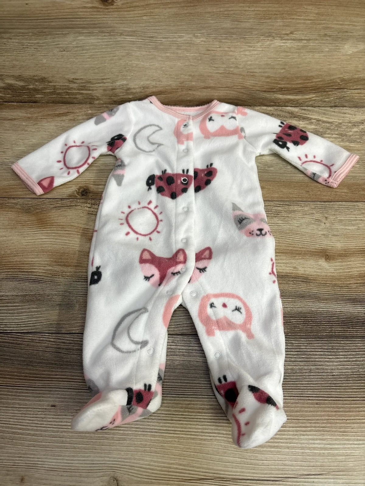 White baby fleece footed sleeper with pink and black animal and sun prints, snap closure