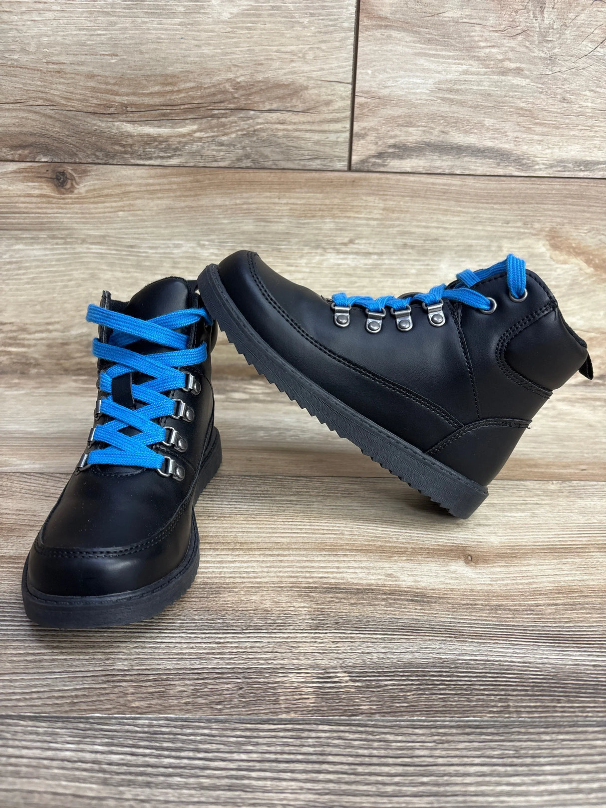 Black kids' lace-up boots with bright blue laces on a wood background