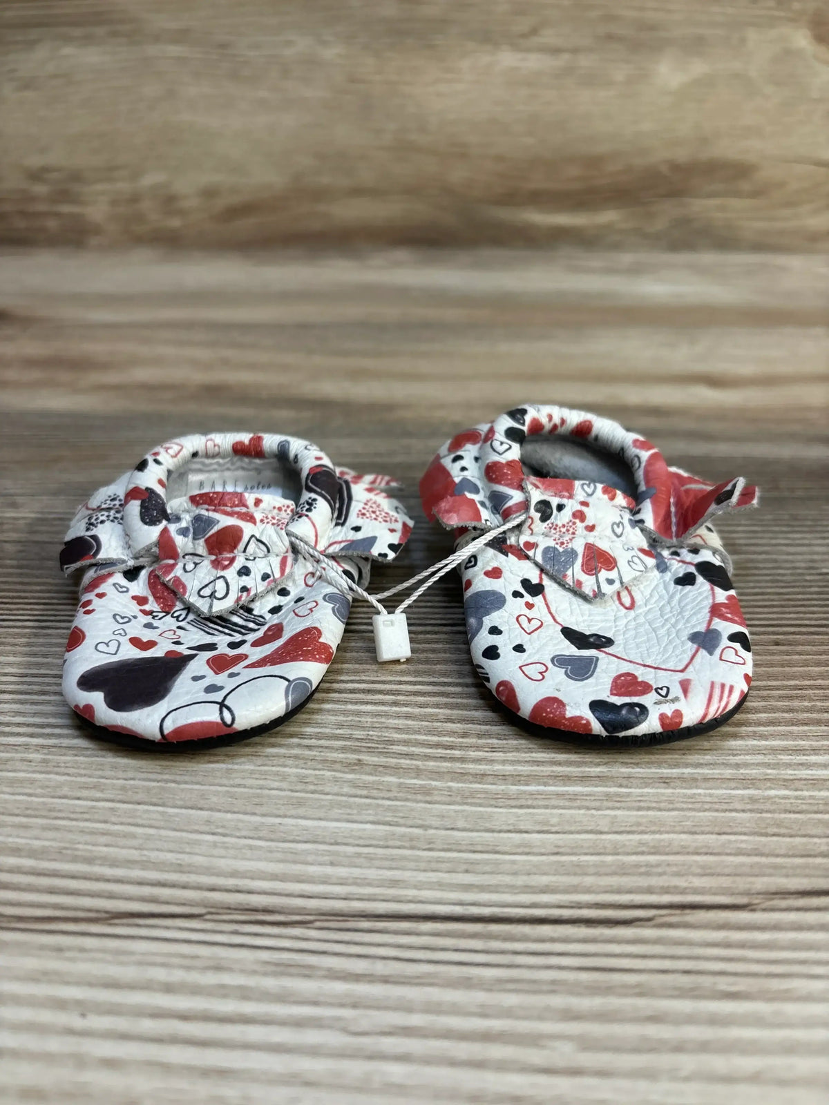 Heart print baby shoes on wooden background, soft sole, infant footwear