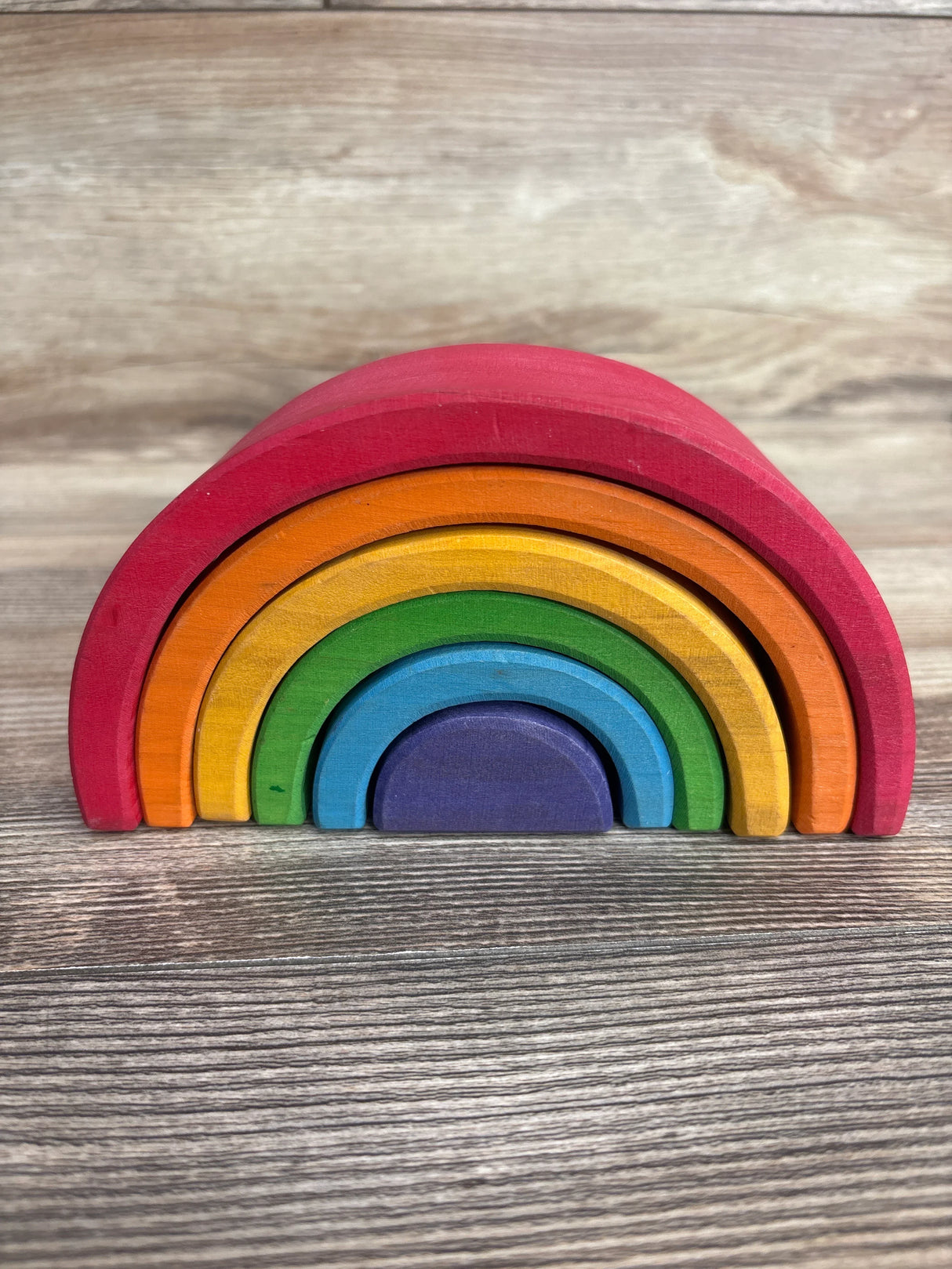 Wooden rainbow stacking toy with colorful arches on a wood surface
