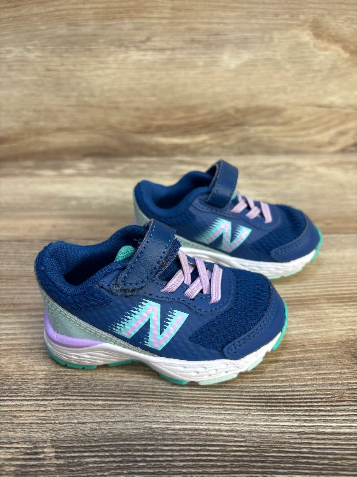 Navy blue toddler sneakers with purple laces and Velcro strap on wood background