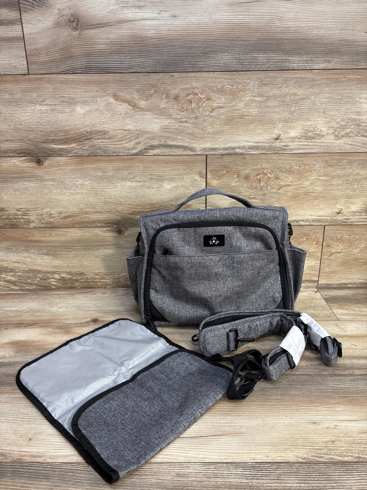 Gray diaper bag set with changing mat and strap on wood background