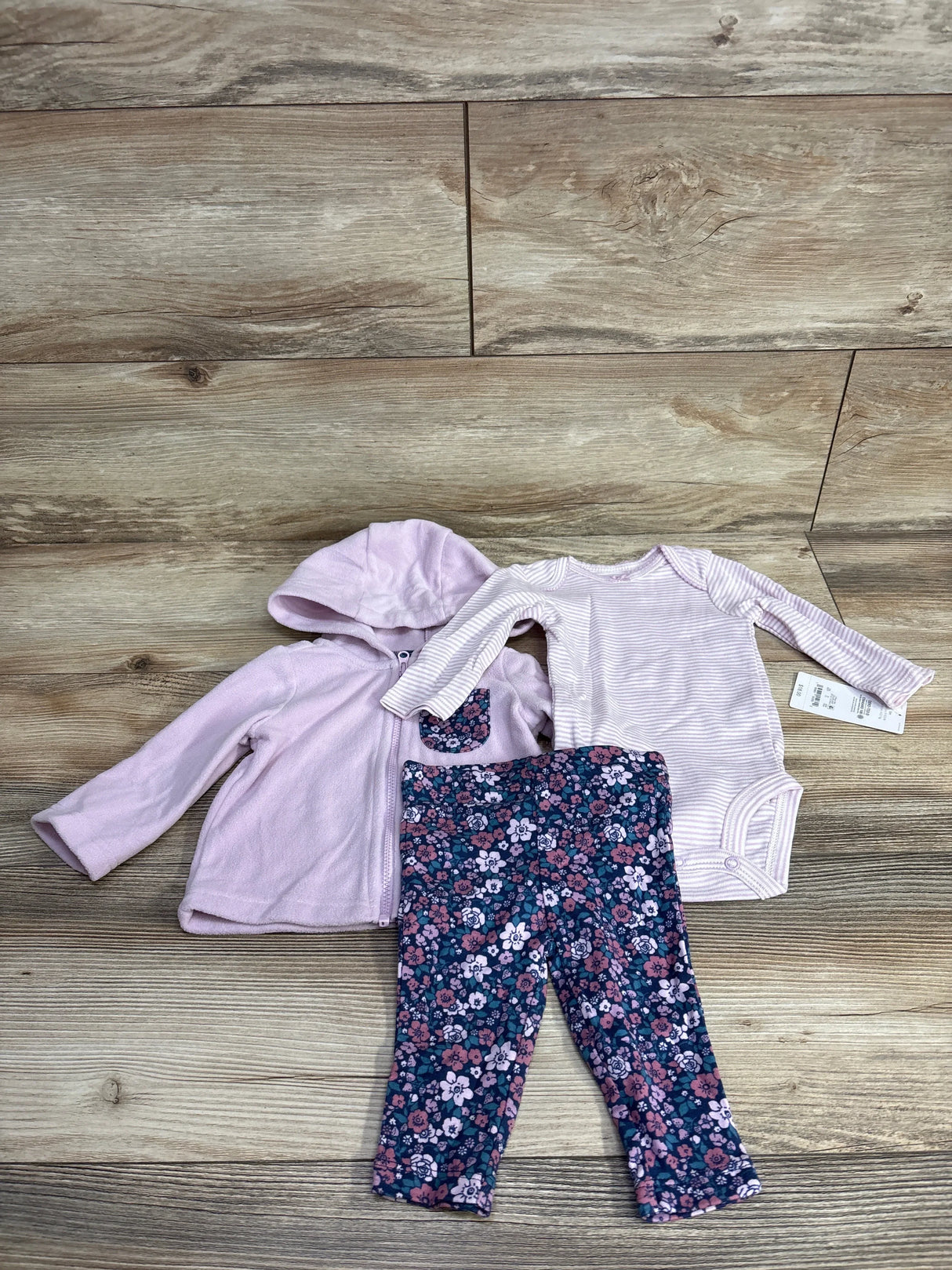 Baby girl outfit set with pink hoodie, striped bodysuit, and floral leggings on wood floor