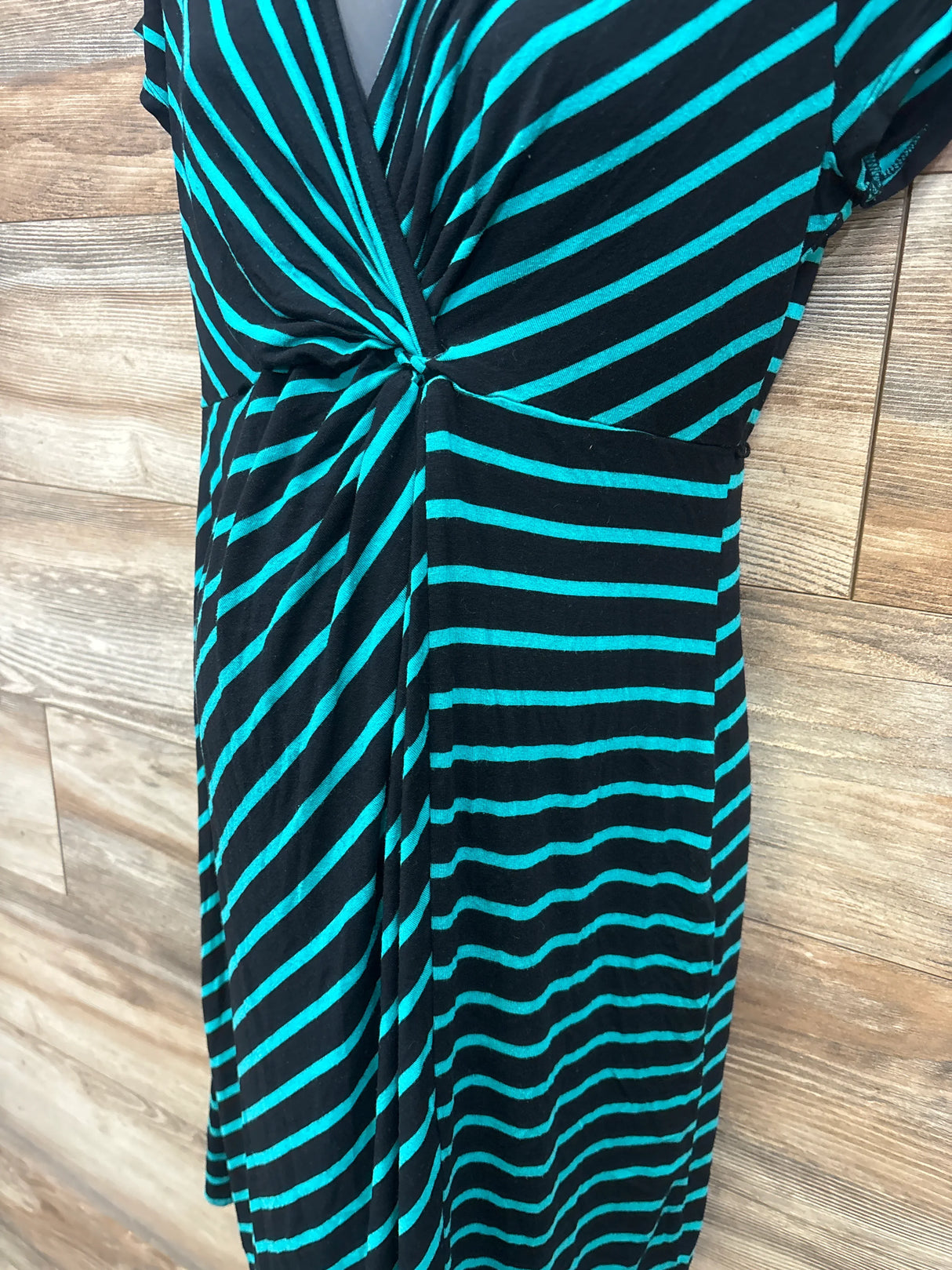 Black and teal striped short-sleeve maternity dress with knot detail on wood background