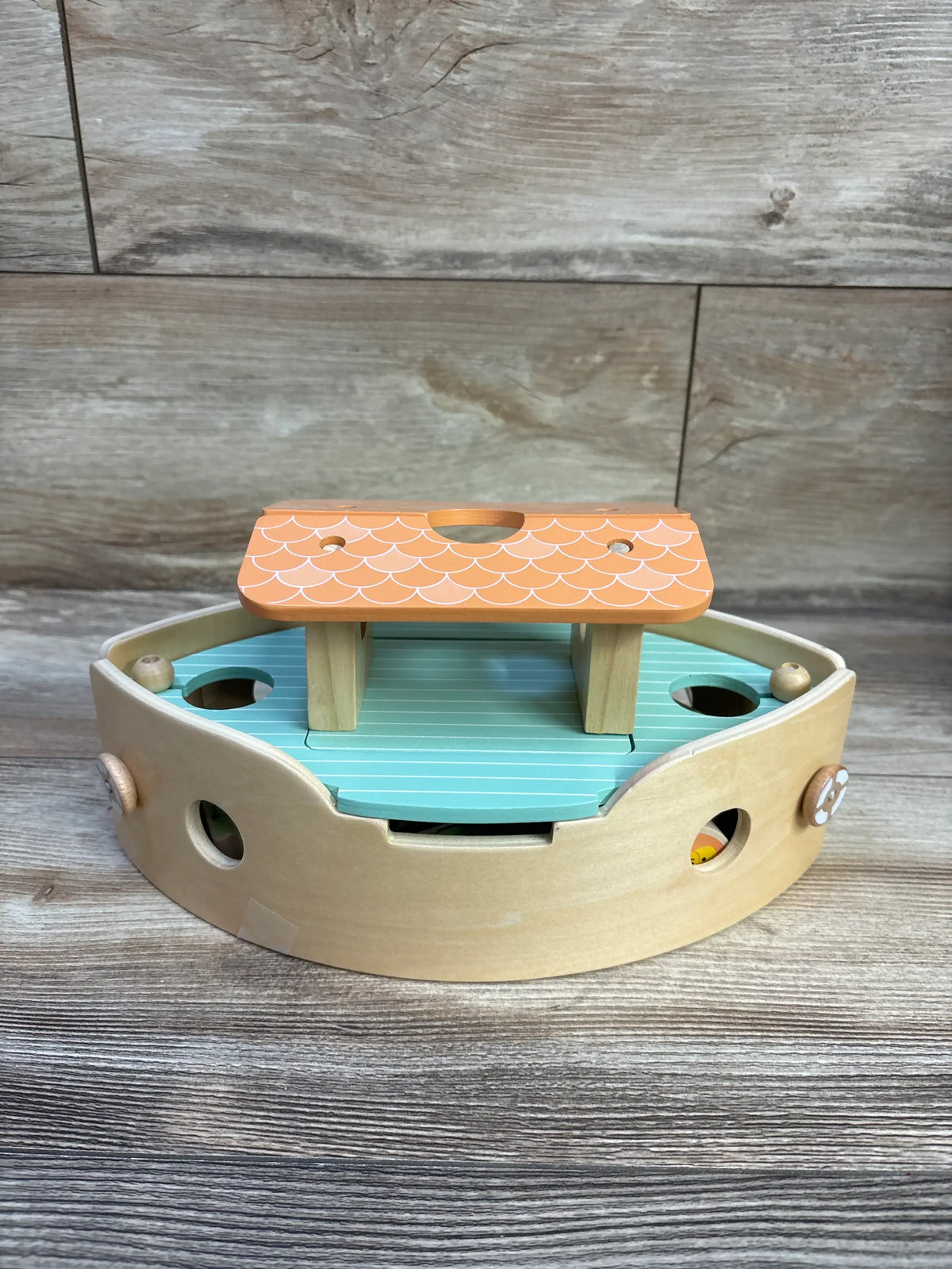 Front view of Classic World Noah’s Ark wooden playset showing orange scalloped roof and teal deck with peg holes on wood plank background