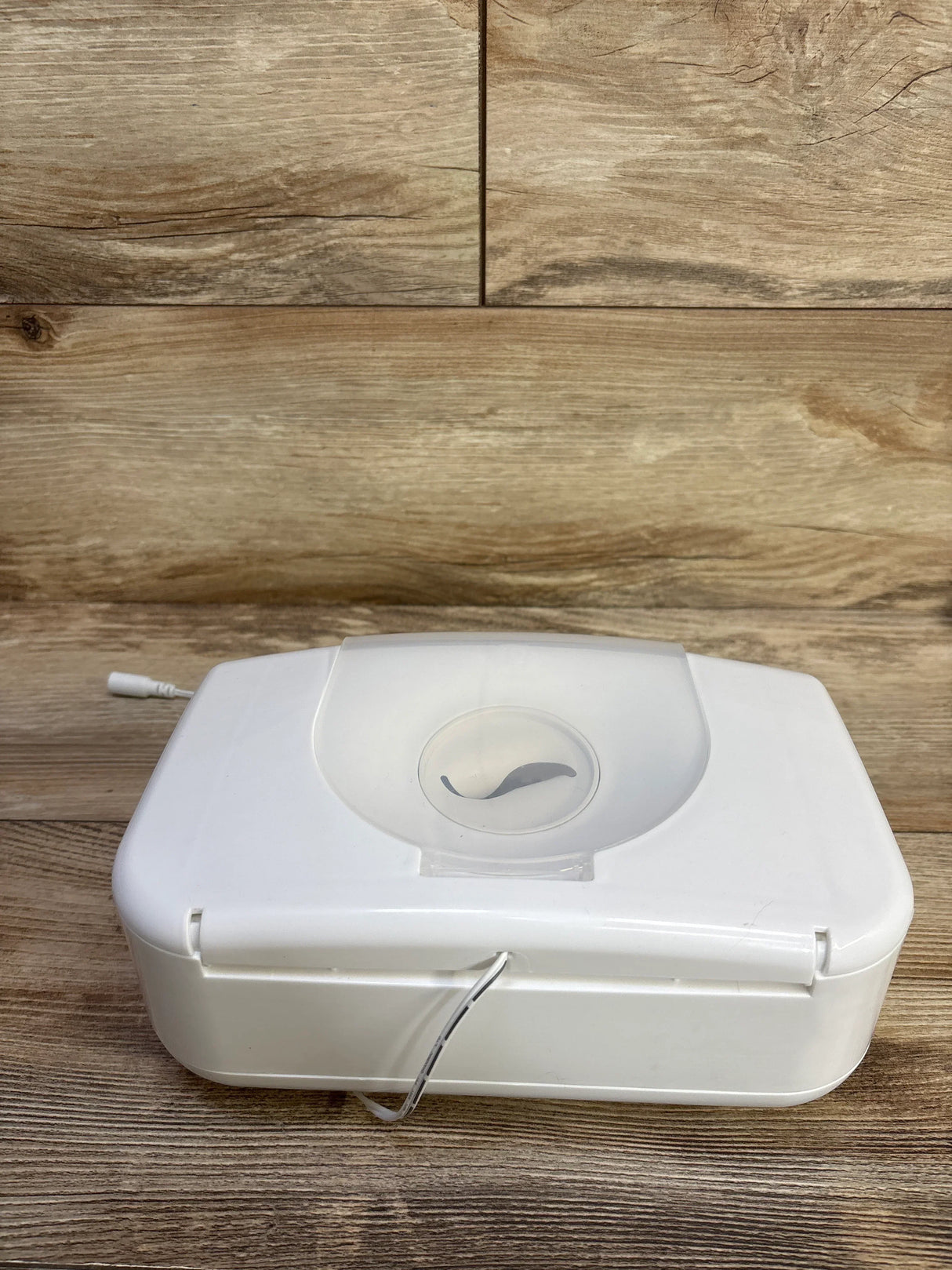 Front view of Munchkin wipe warmer white showing top flip lid with leaf logo and power cord on wood background
