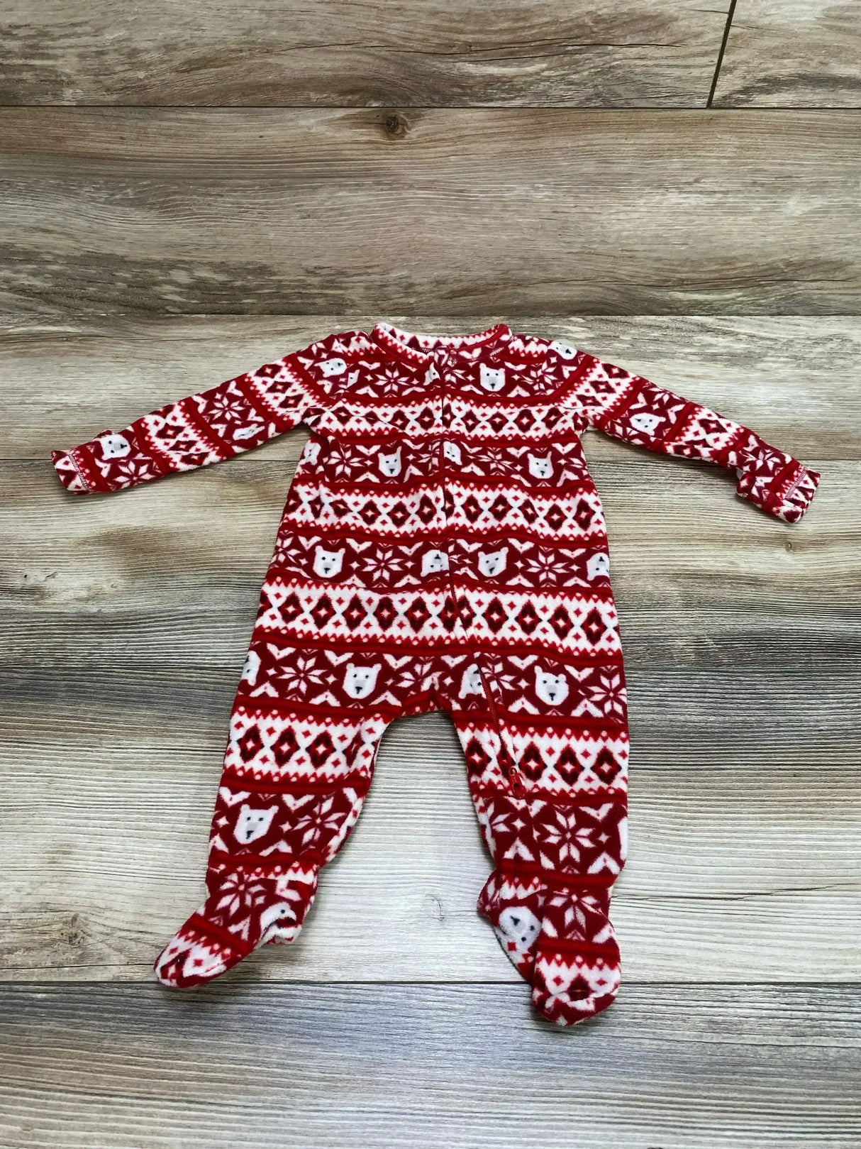 Flat lay of red Old Navy Fair Isle footed baby sleeper showing front zipper and polar bear patterned knit on wood background