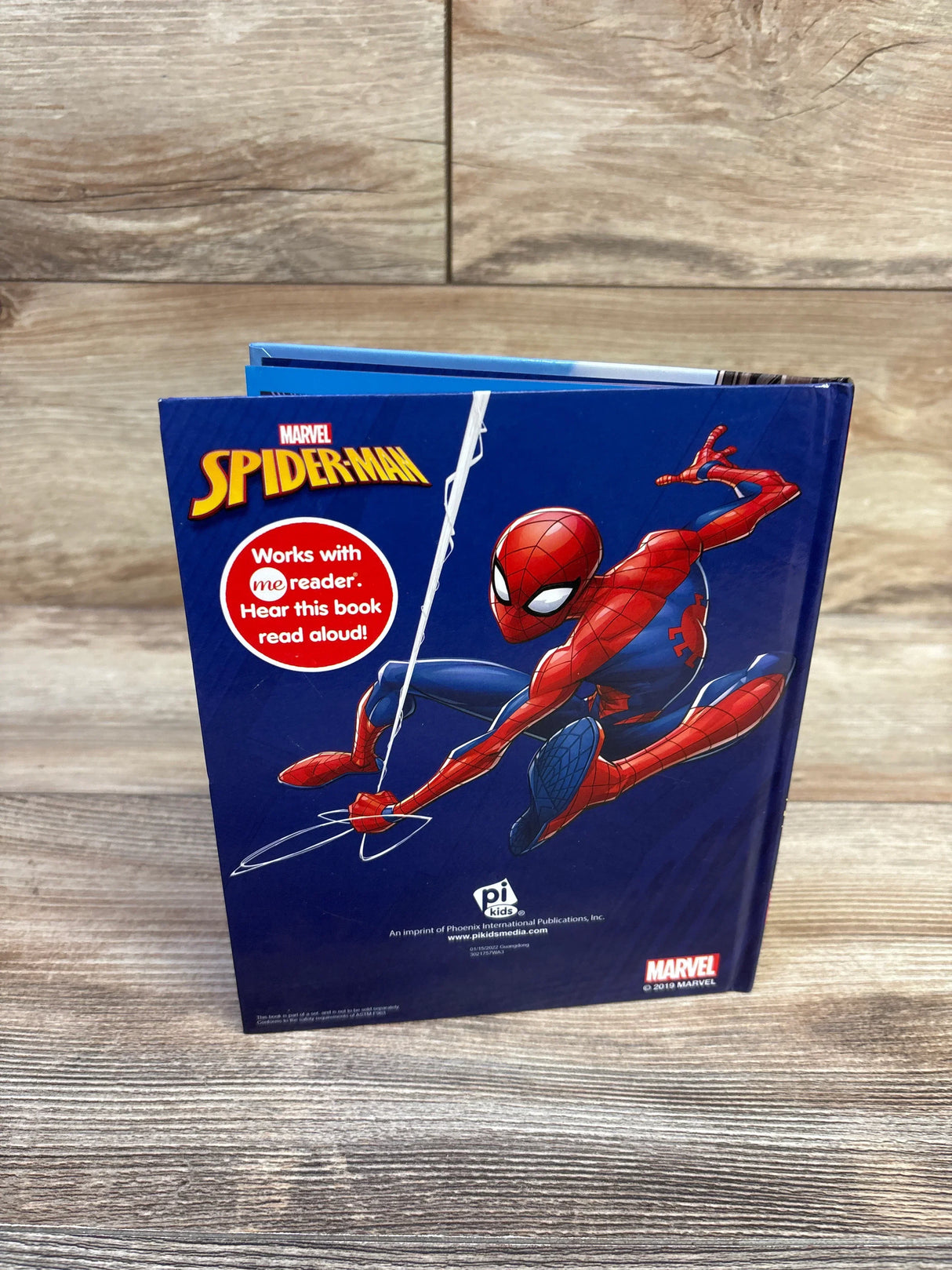 Front view of Marvel Spider-Man hardcover book showing Spider-Man and a red Works with me reader badge on wood tabletop