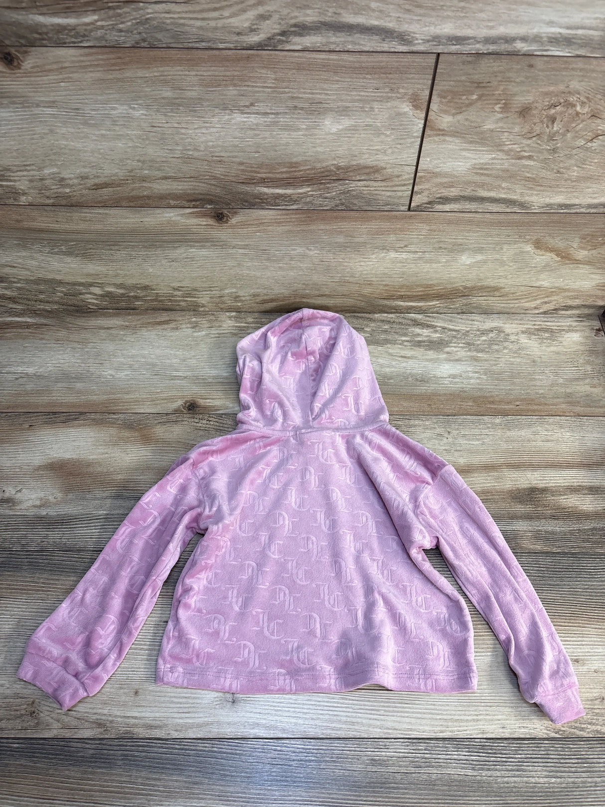 Pink kids hoodie with monogram pattern, soft fabric, laid on wood floor