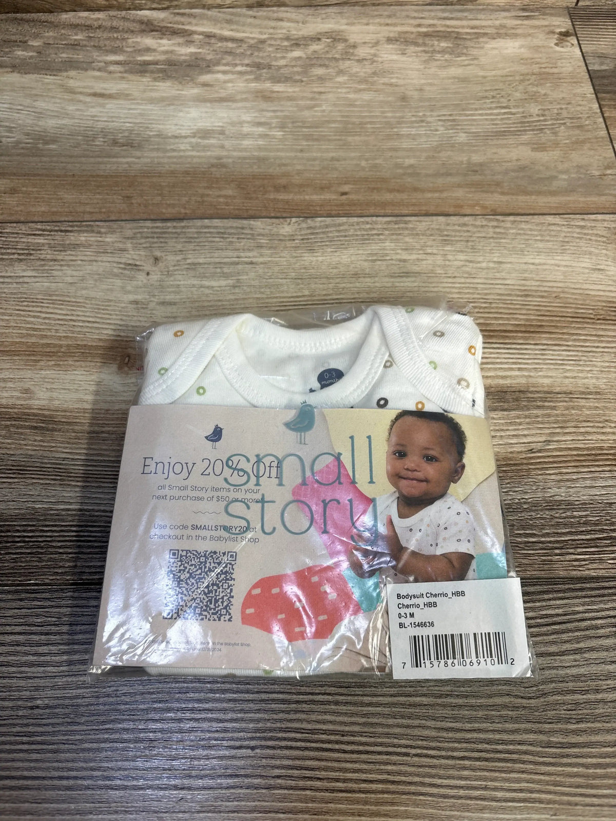 Top view of Small Story Cheerio bodysuit showcasing a white base with multicolored ring pattern in clear packaging