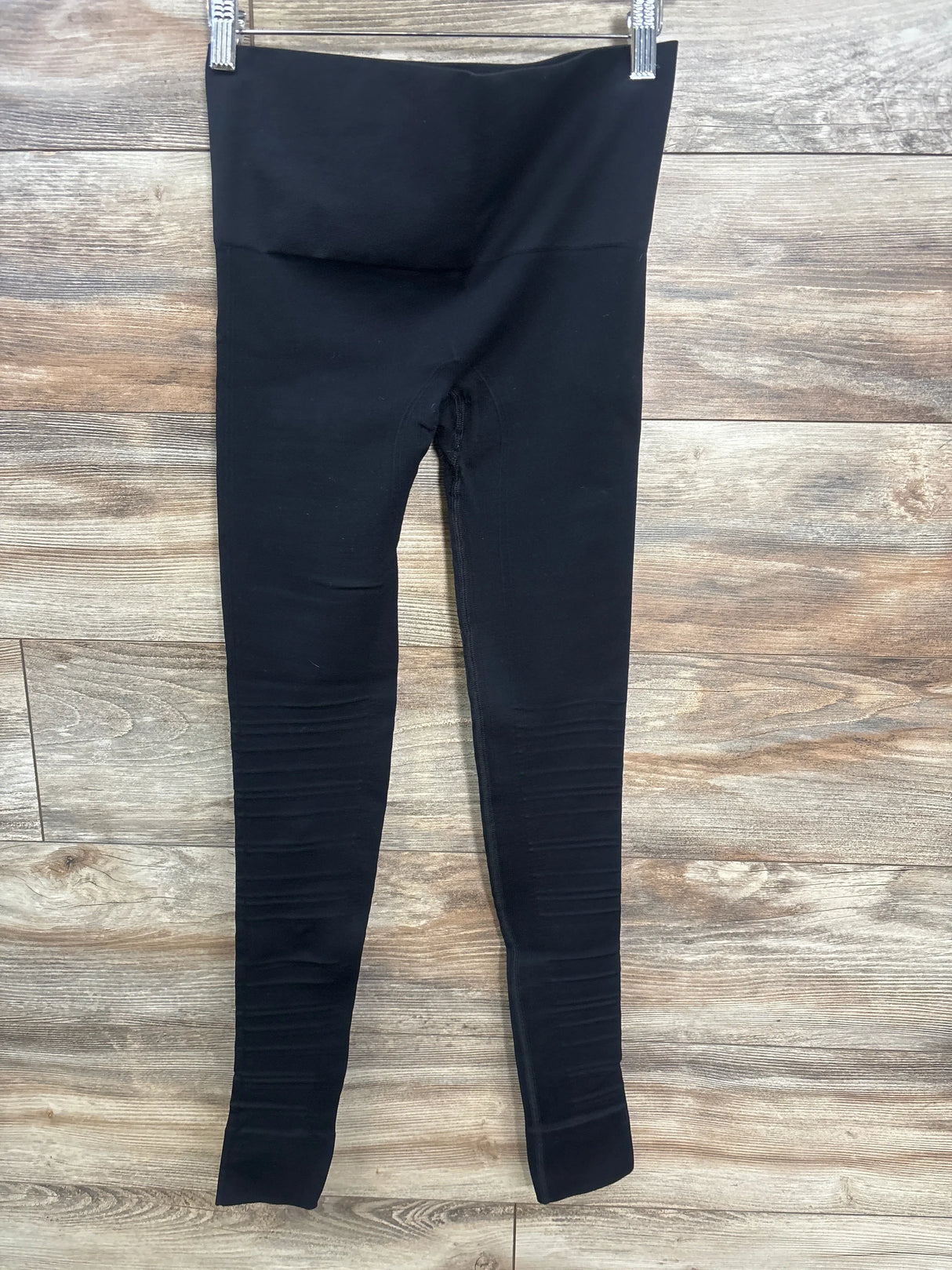 Black maternity leggings with high waistband displayed on wooden background