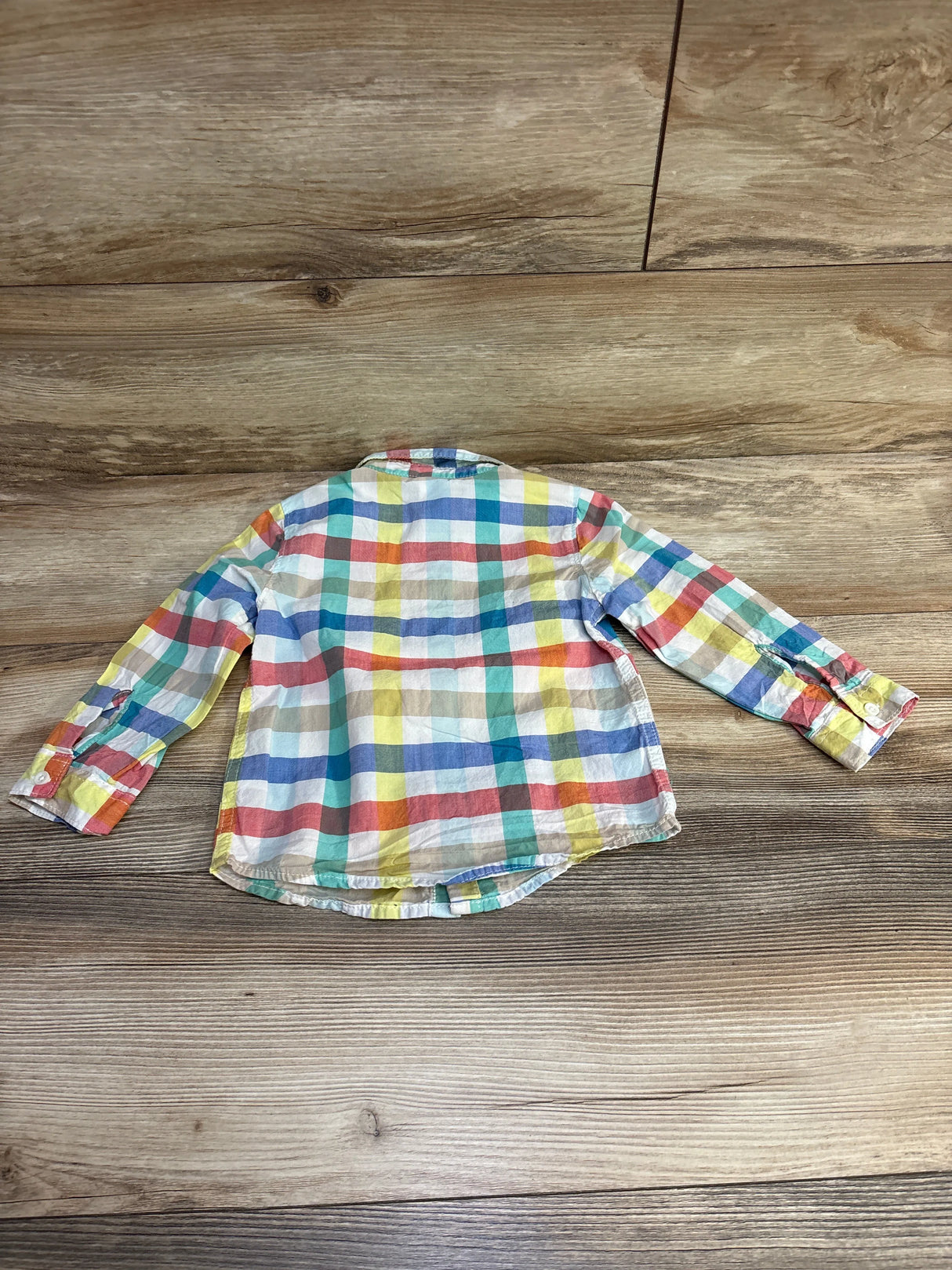 Colorful plaid long sleeve shirt laid flat on wooden floor